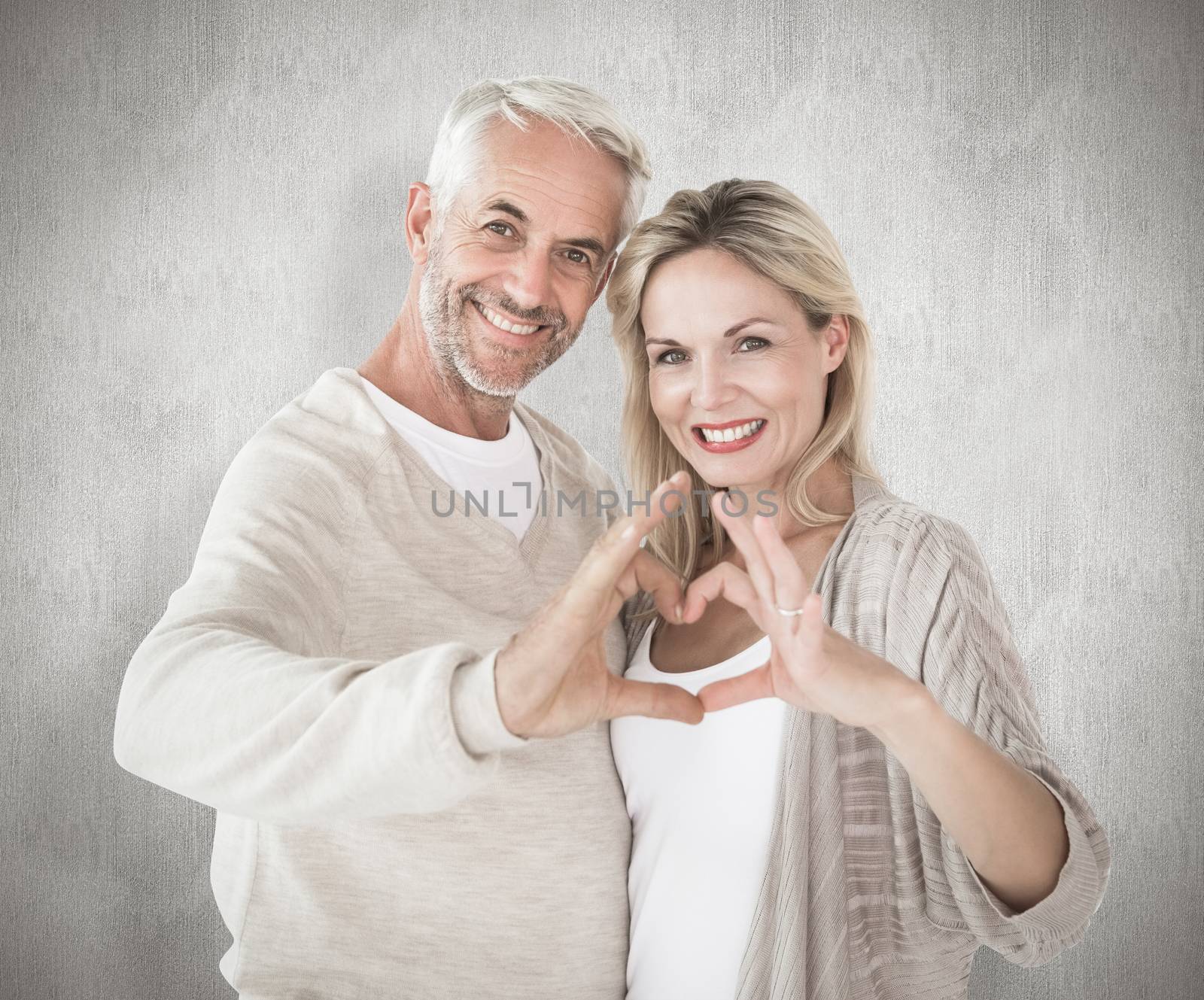 Happy couple forming heart shape with hands against white background