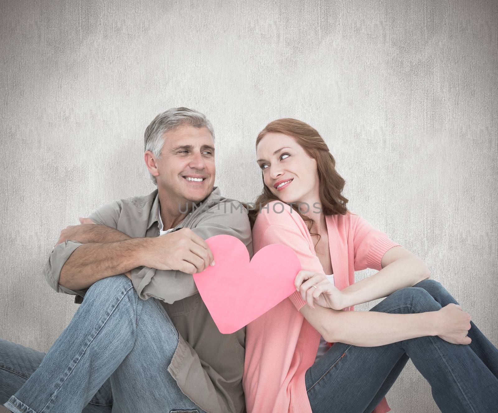 Casual couple holding pink heart against white background