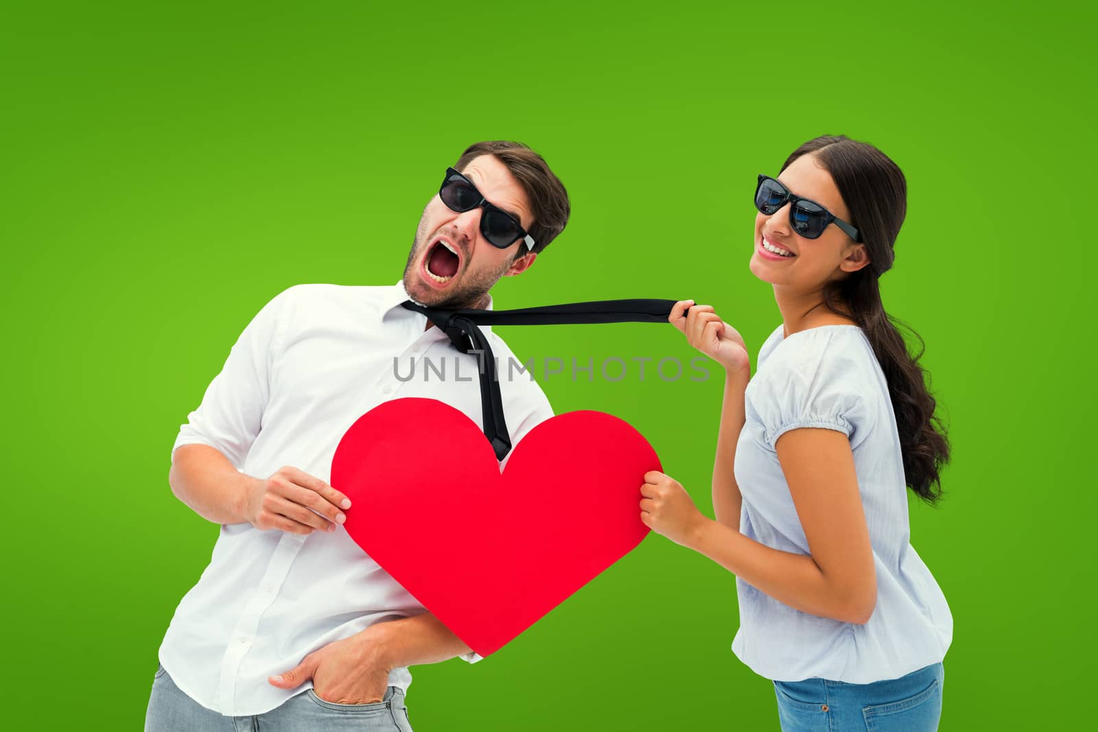 Brunette pulling her boyfriend by the tie holding heart against green vignette