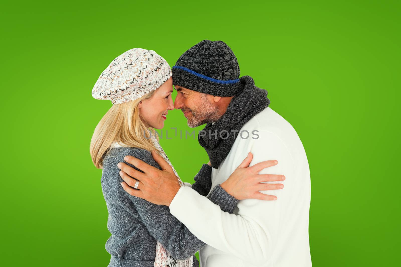 Happy couple in winter fashion embracing against green vignette