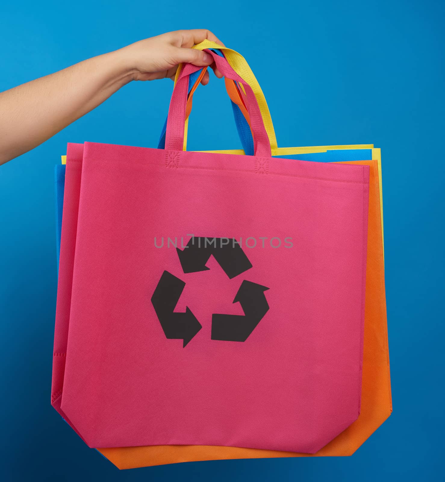 woman's hand holds a pink viscose ecology bag, recyclable material, blue background