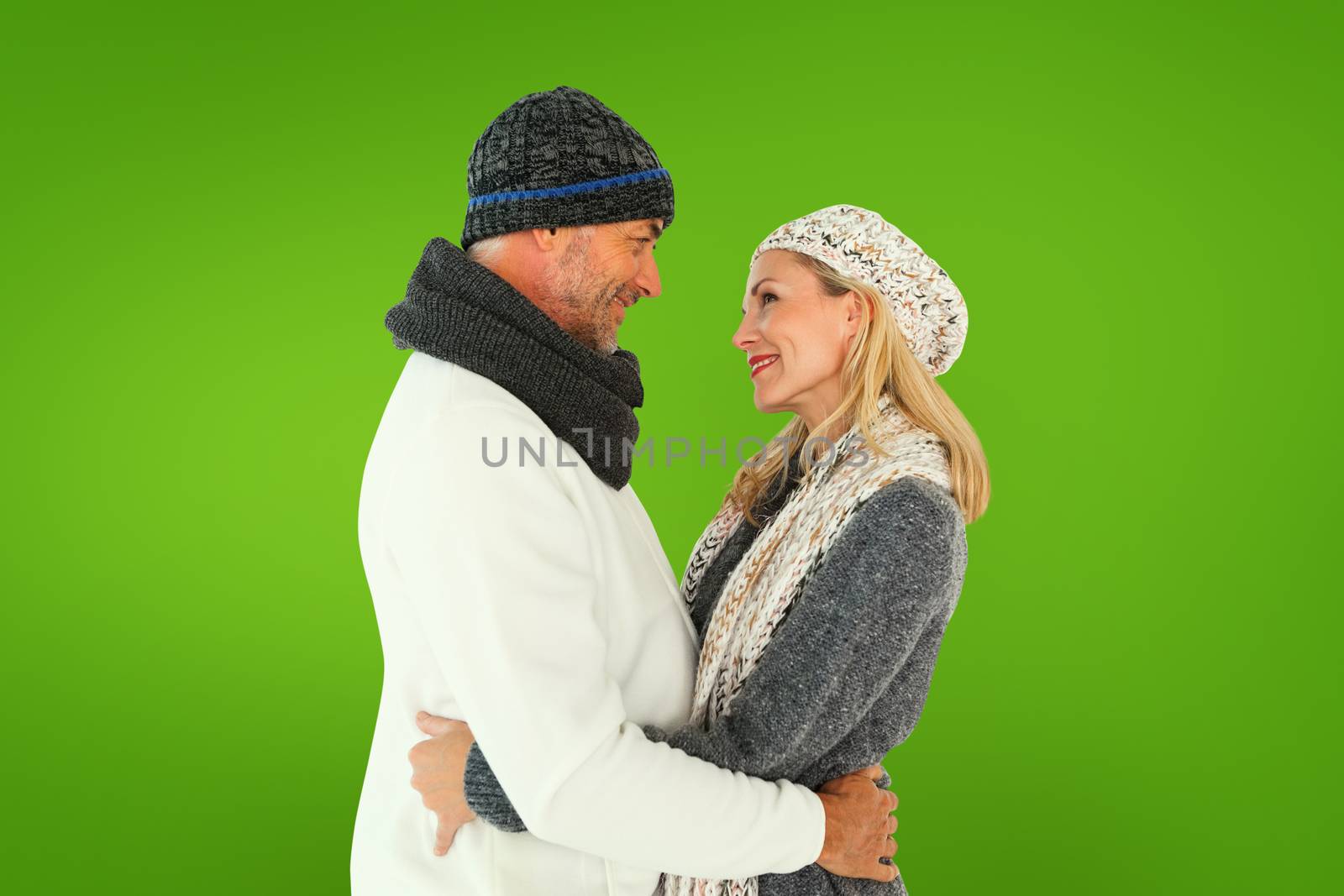 Happy couple in winter fashion embracing against green vignette