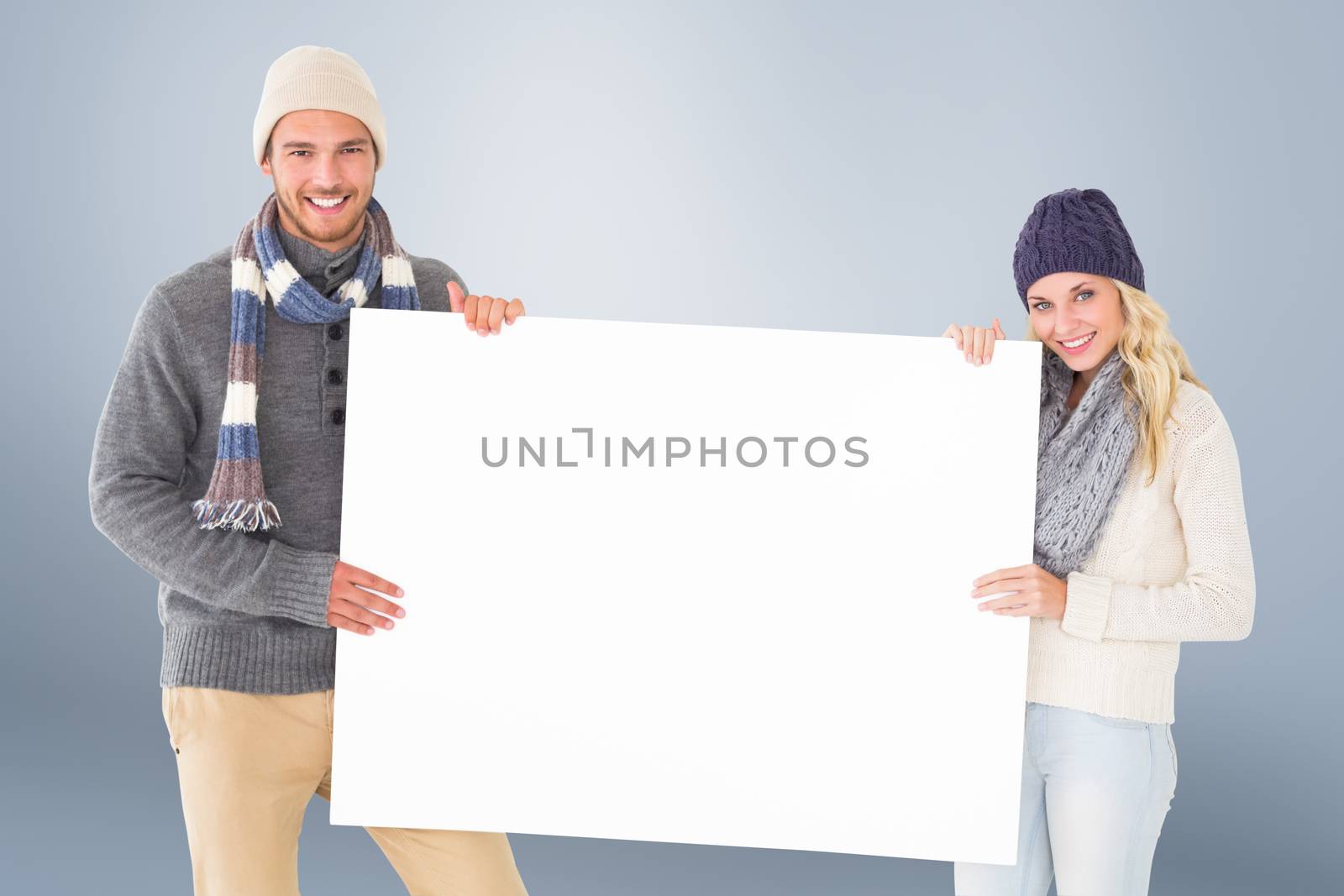Attractive couple in winter fashion showing poster by Wavebreakmedia