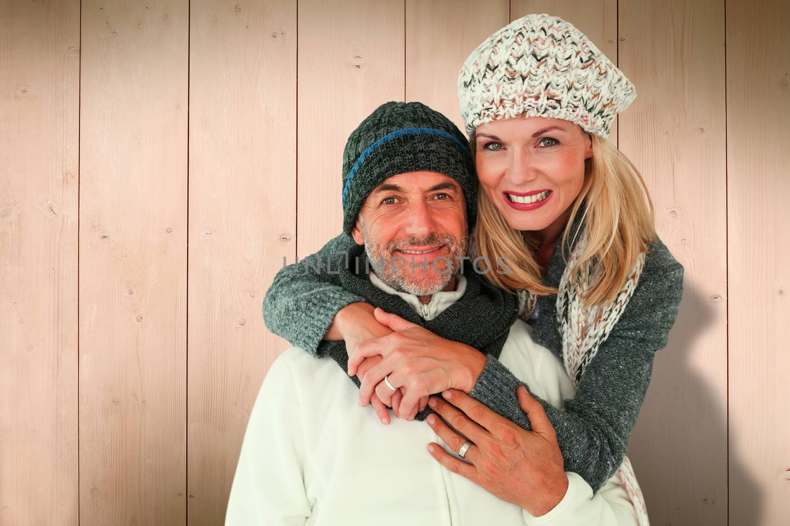Happy couple in winter fashion embracing against wooden planks