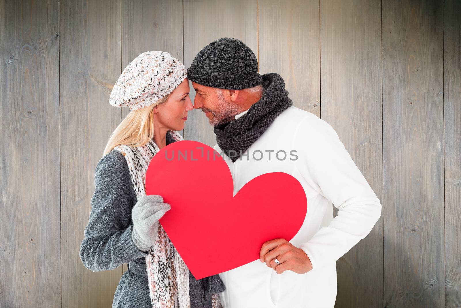 Composite image of smiling couple in winter fashion posing with heart shape by Wavebreakmedia