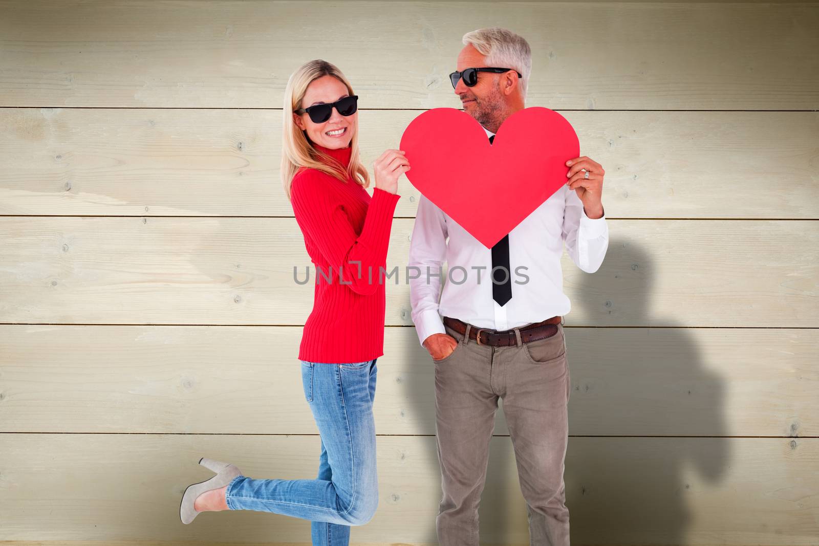 Composite image of cool couple holding a red heart together by Wavebreakmedia