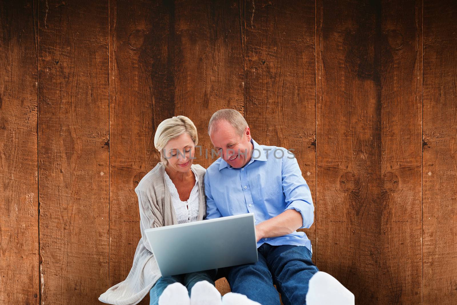 Composite image of happy mature couple using laptop by Wavebreakmedia