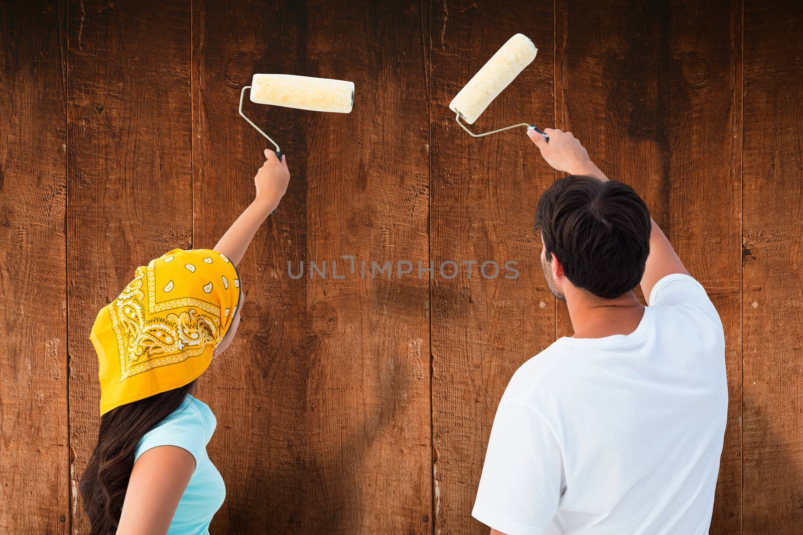 Happy young couple painting together against weathered oak floor boards background