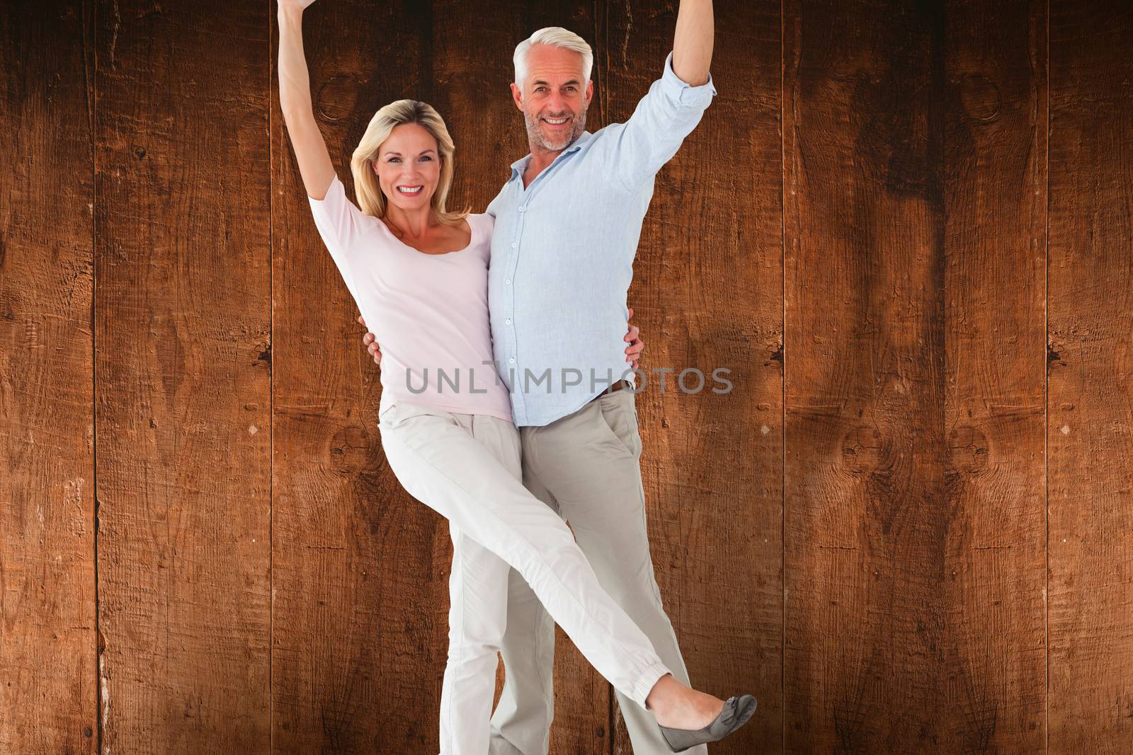 Smiling couple cheering at the camera against weathered oak floor boards background