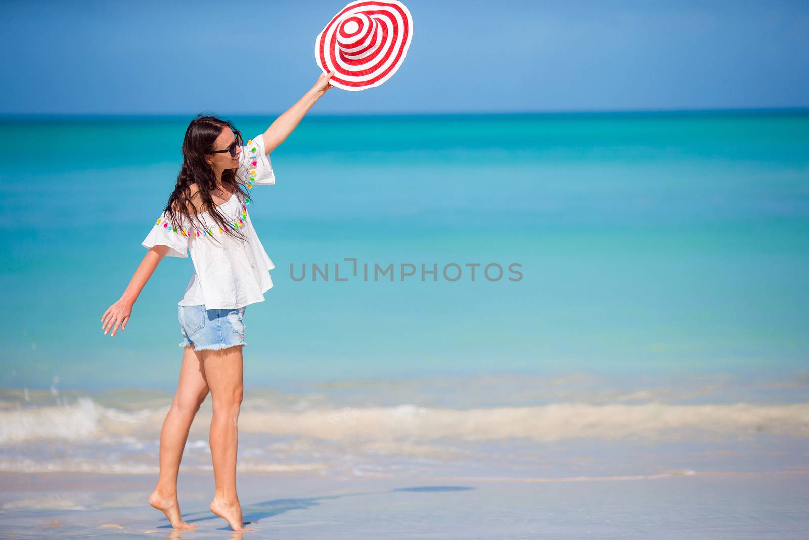 Young beautiful woman on white sand tropical beach. Caucasian girl with hat background the sea by travnikovstudio