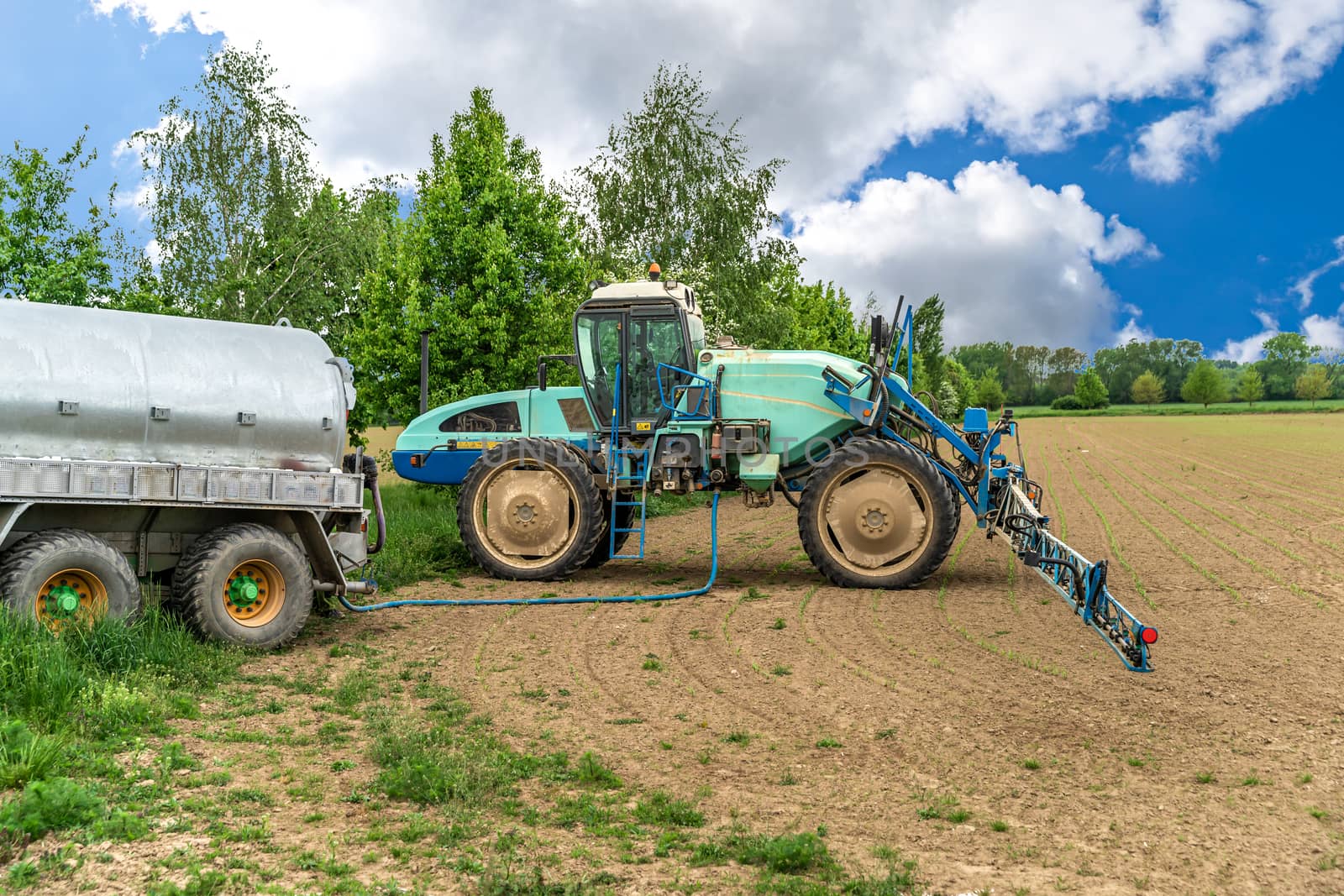 chemicals against weeds refueled in the tank of a tractor with a sprayer by Edophoto