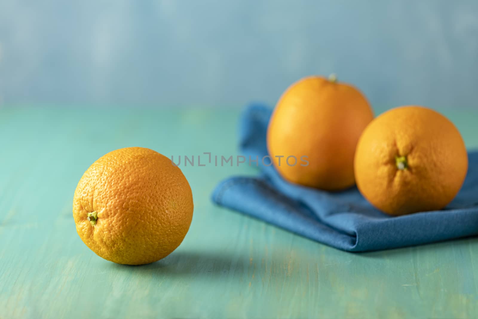 Three ripe juicy orange on wooden turquoise table surface. Close up, copy space for you text, shallow depth of the field. 