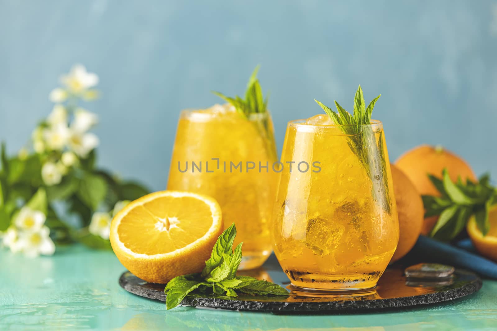 Two glass of orange ice drink with fresh mint on wooden turquois by ArtSvitlyna