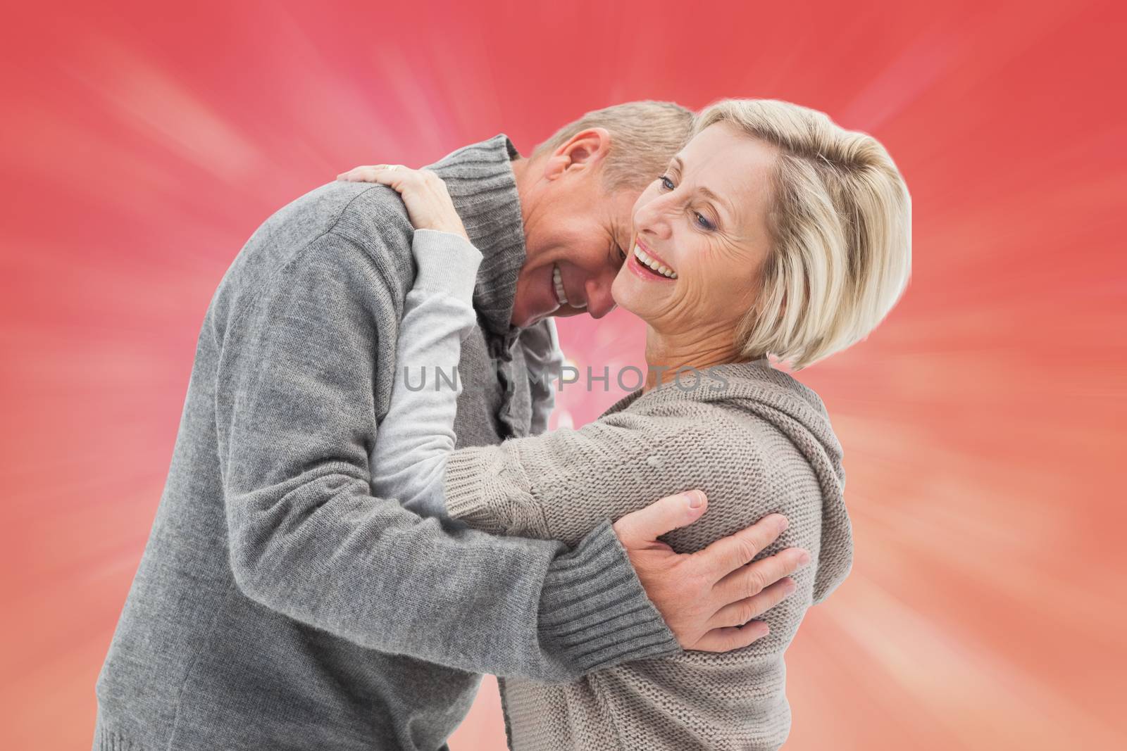 Happy mature couple in winter clothes against red abstract light spot design