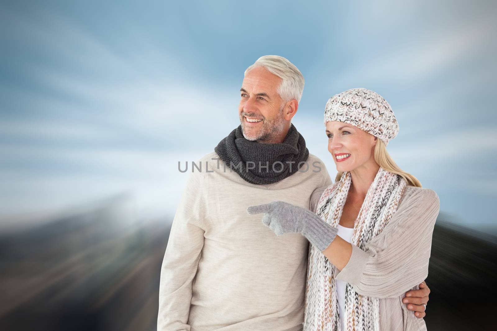 Happy couple in winter fashion looking against large rock overlooking big city
