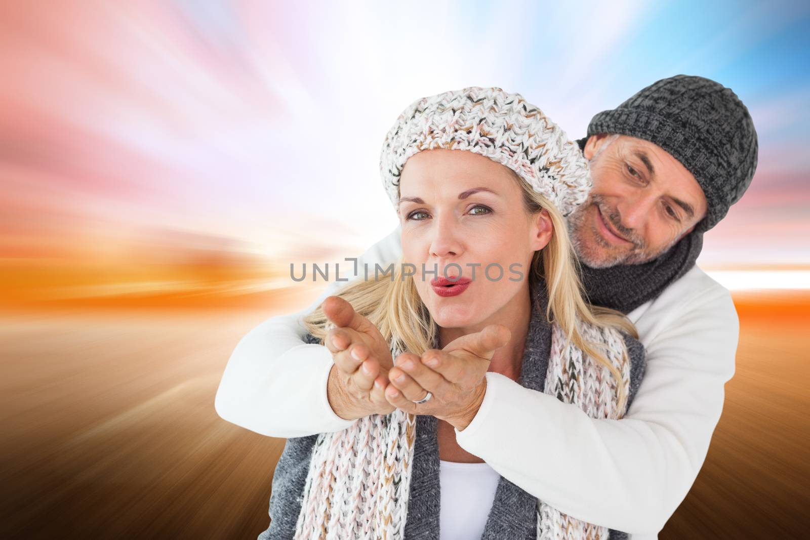 Smiling couple in winter fashion posing against field with light wave