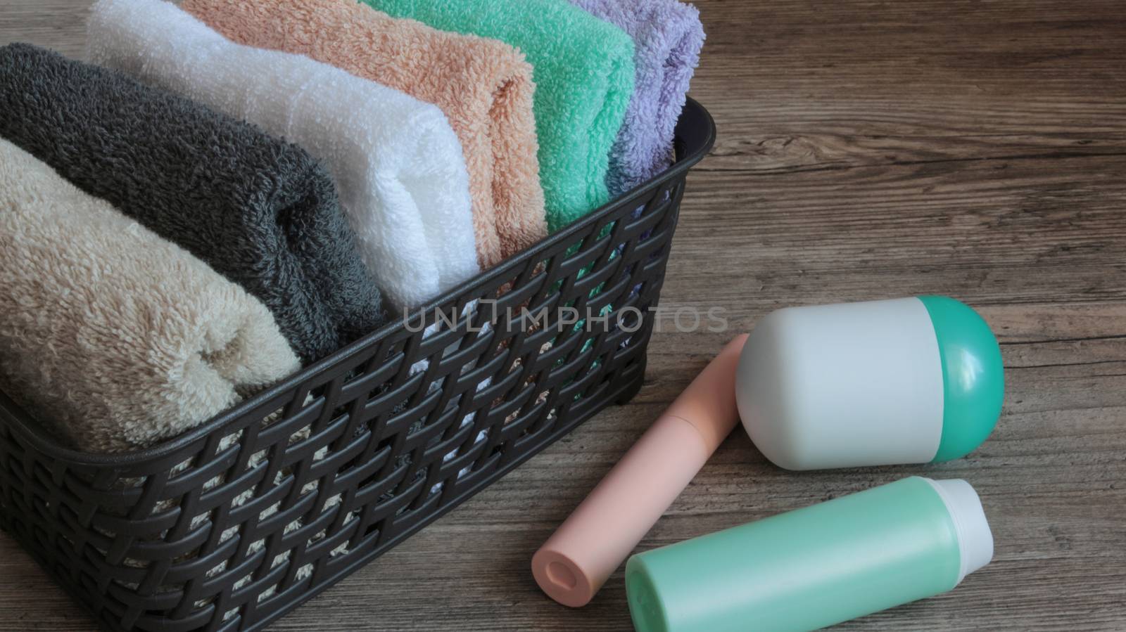 colorful towels and cosmetics in a basket on a wooden table