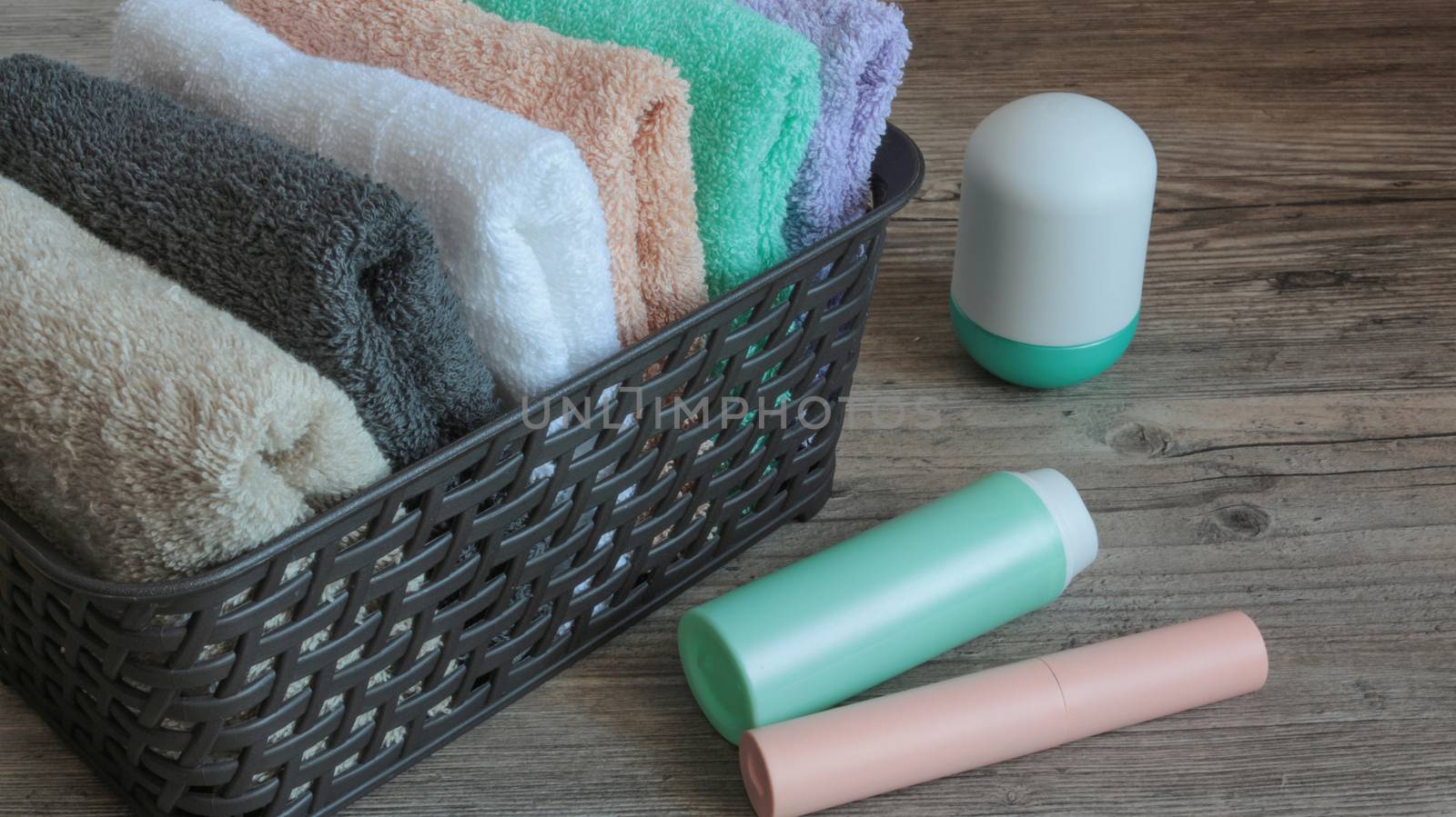 colorful towels and cosmetics in a basket on a wooden table