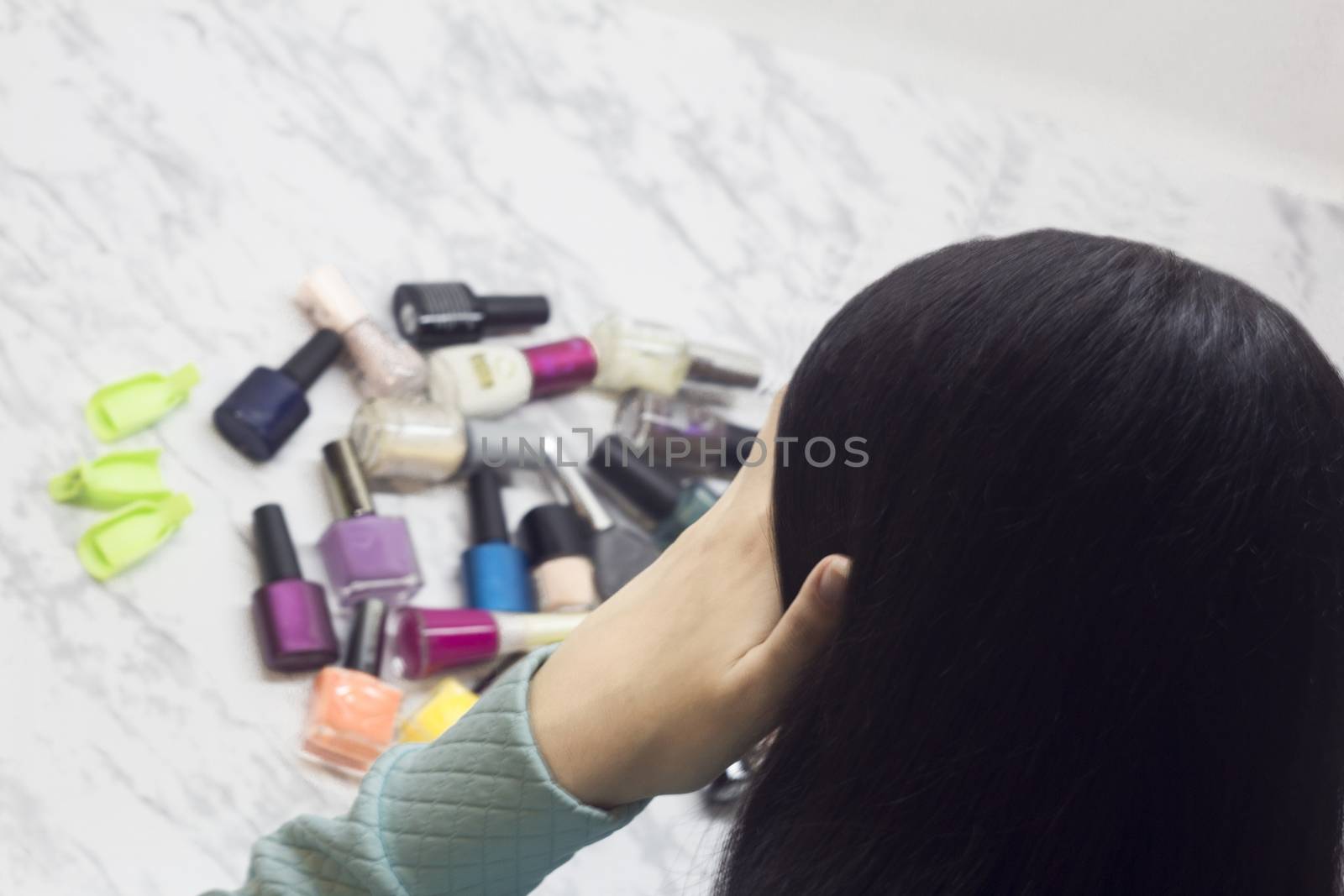Young woman chooses nail polishes, beauty and fashion, difficulty of choice, dilemma, Spa salon at home,