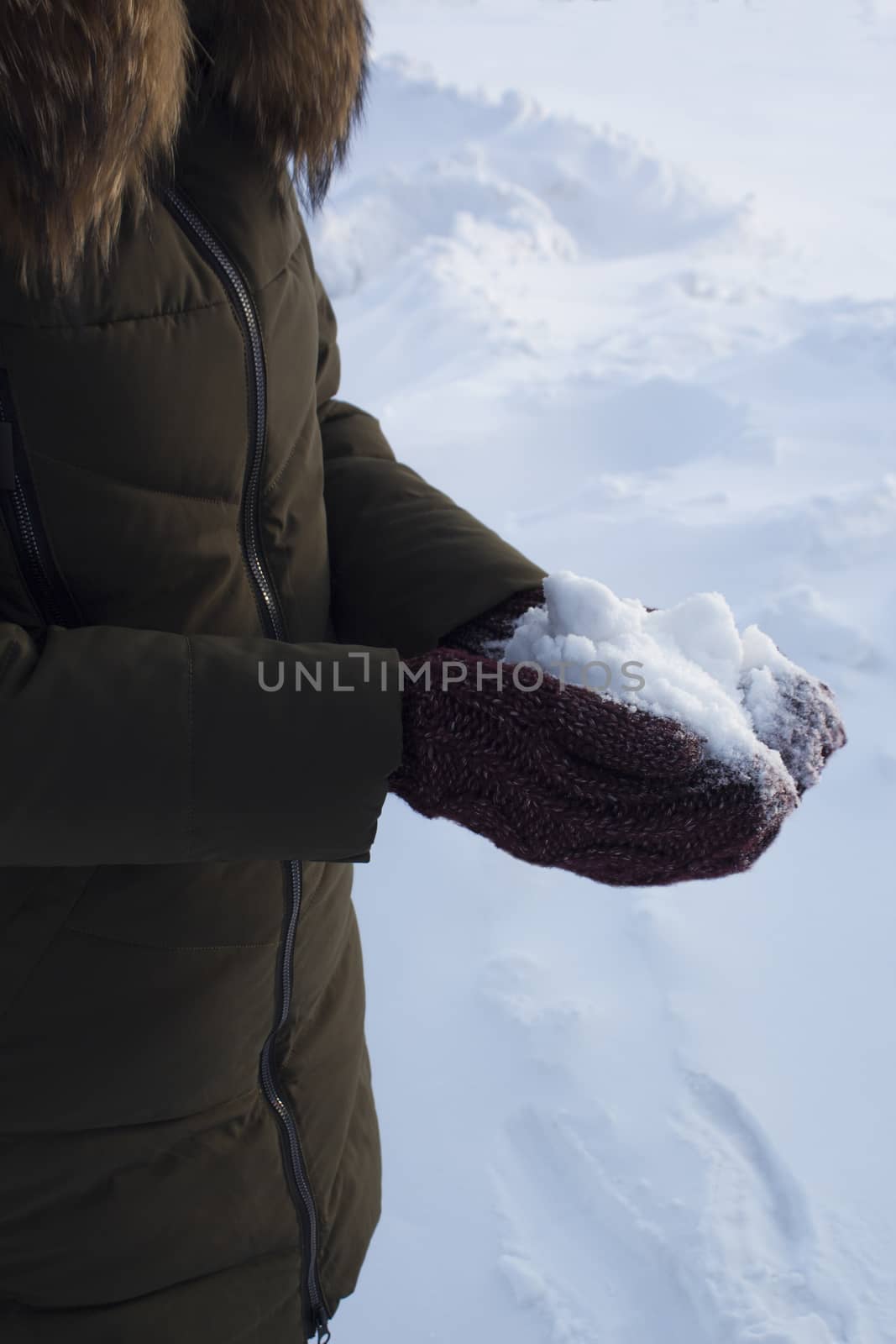 Man holding snowball winter in the Park, walk, fun, sports and leisure, green jacket, Burgundy mittens