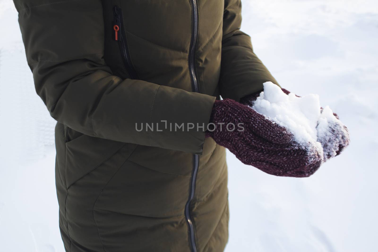 Young girl holding snow in her hands in mittens, winter, fun, joy, sports, recreation, children