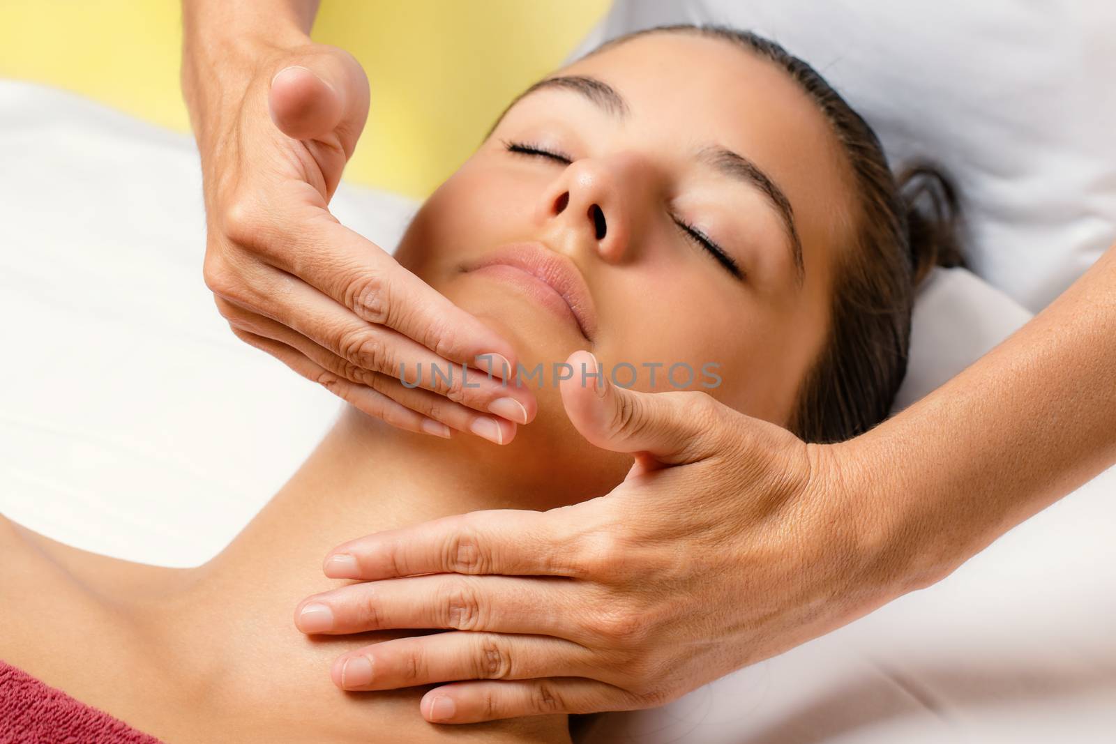 Close up portrait of woman at cosmetic beauty treatment session.Therapist applying cream with continuous movement on neck.