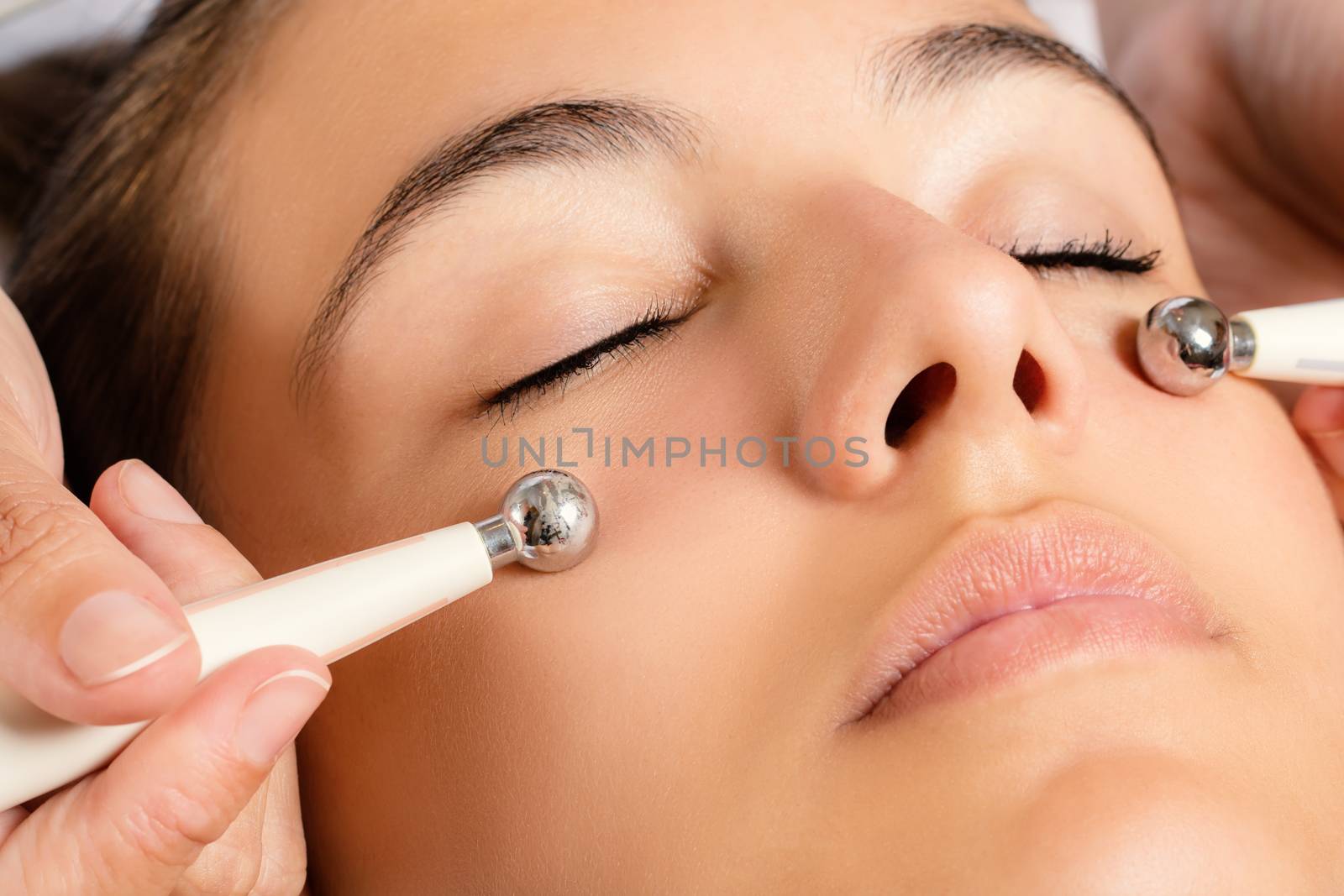 Close up portrait of woman having Galvanic facial treatment with low level current electrodes.