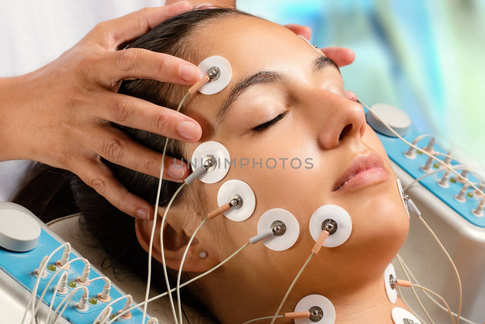 Close up portrait of woman having electrical facial skin tightening treatment.Multiple hypo allergenic pads places on face.
