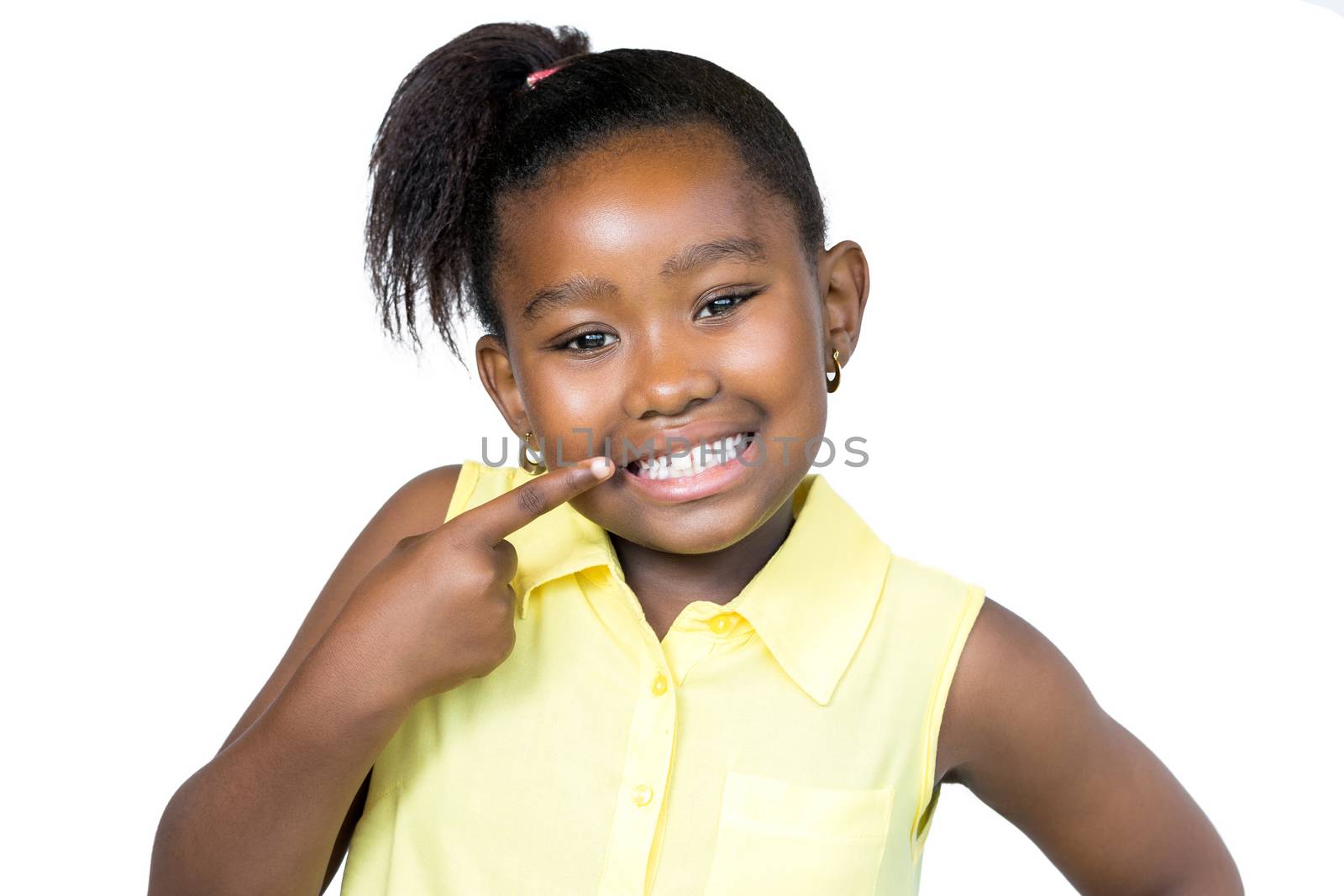 Close up  portrait of cute little african girl with ponytail pointing with finger at teeth.Isolated on white background.