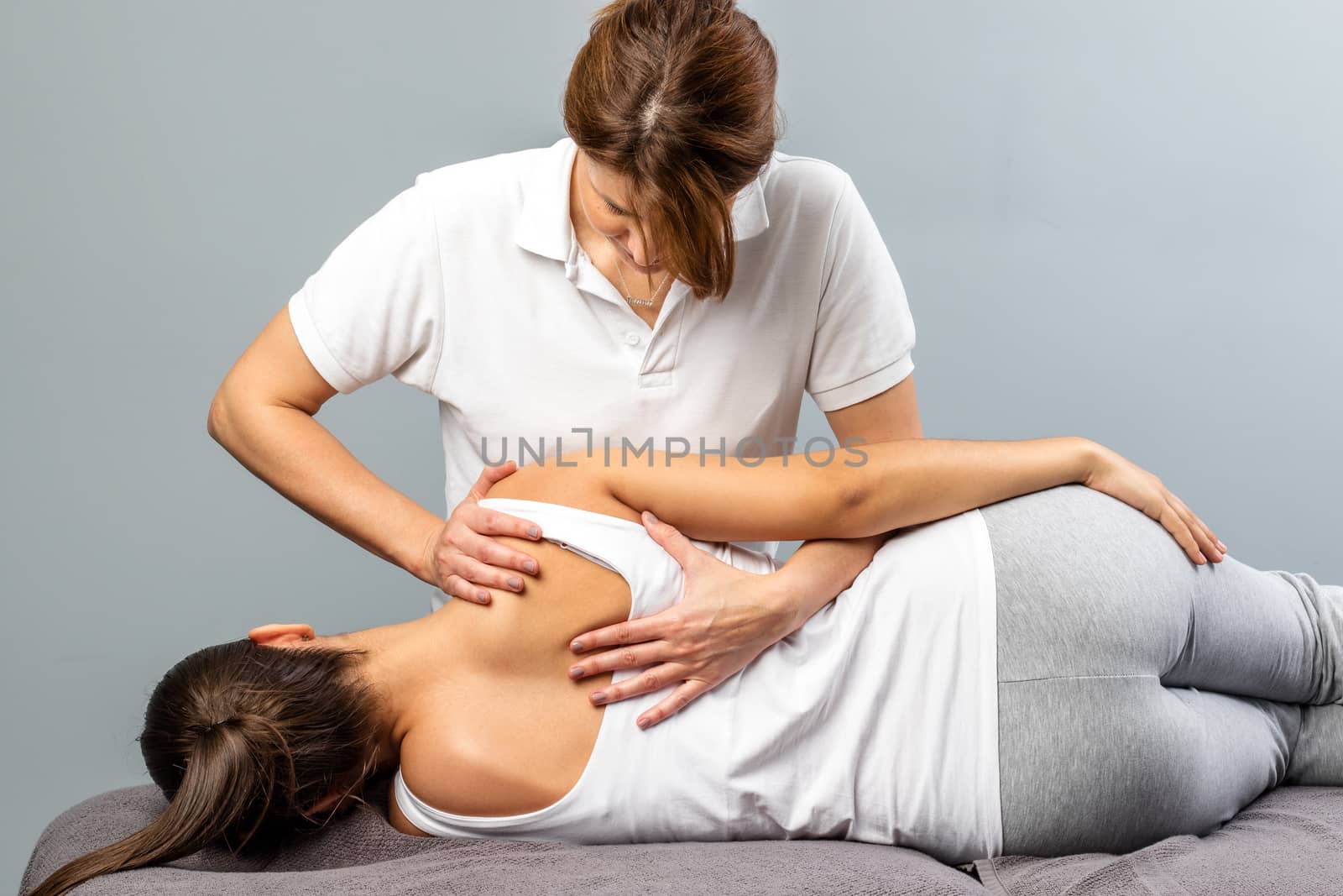 Female therapist manipulating shoulder blade on young female pat by karelnoppe