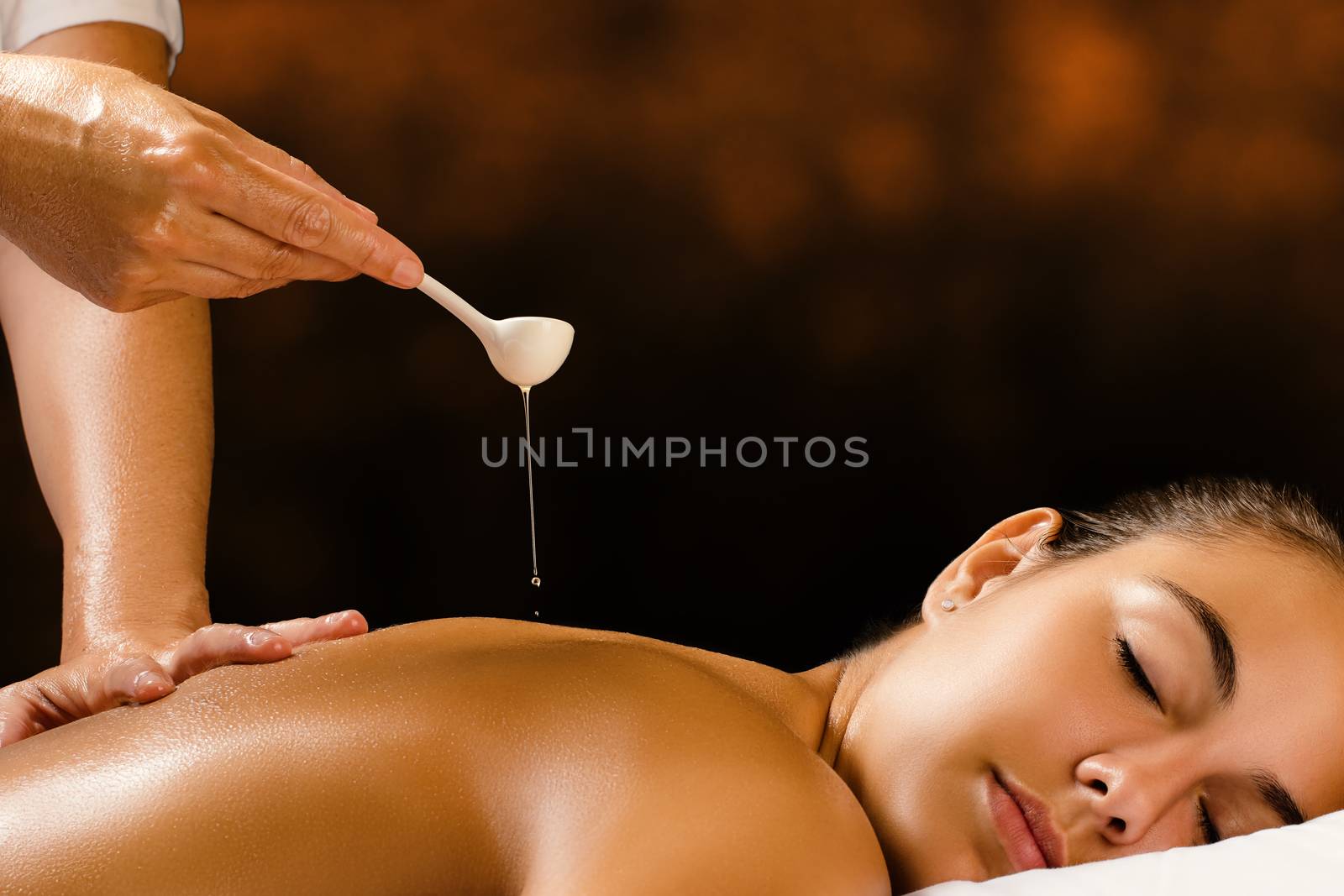 Therapist pouring Ayurvedic oil on female back. by karelnoppe