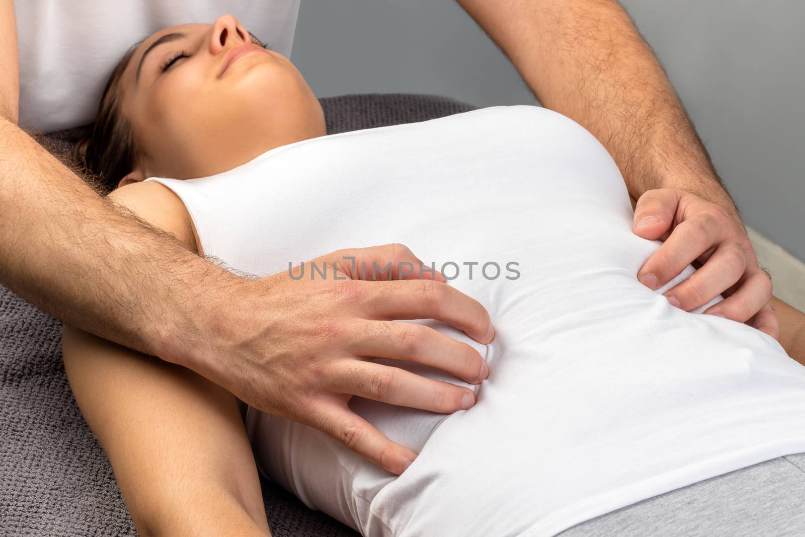 Close up of hands doing physical osteopathic thorax massage on young woman.