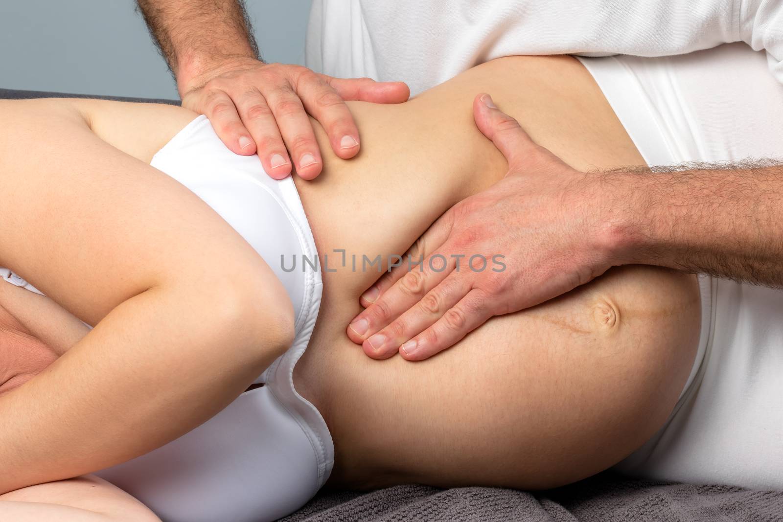 Detail of hands doing physical massage on pregnant belly. by karelnoppe