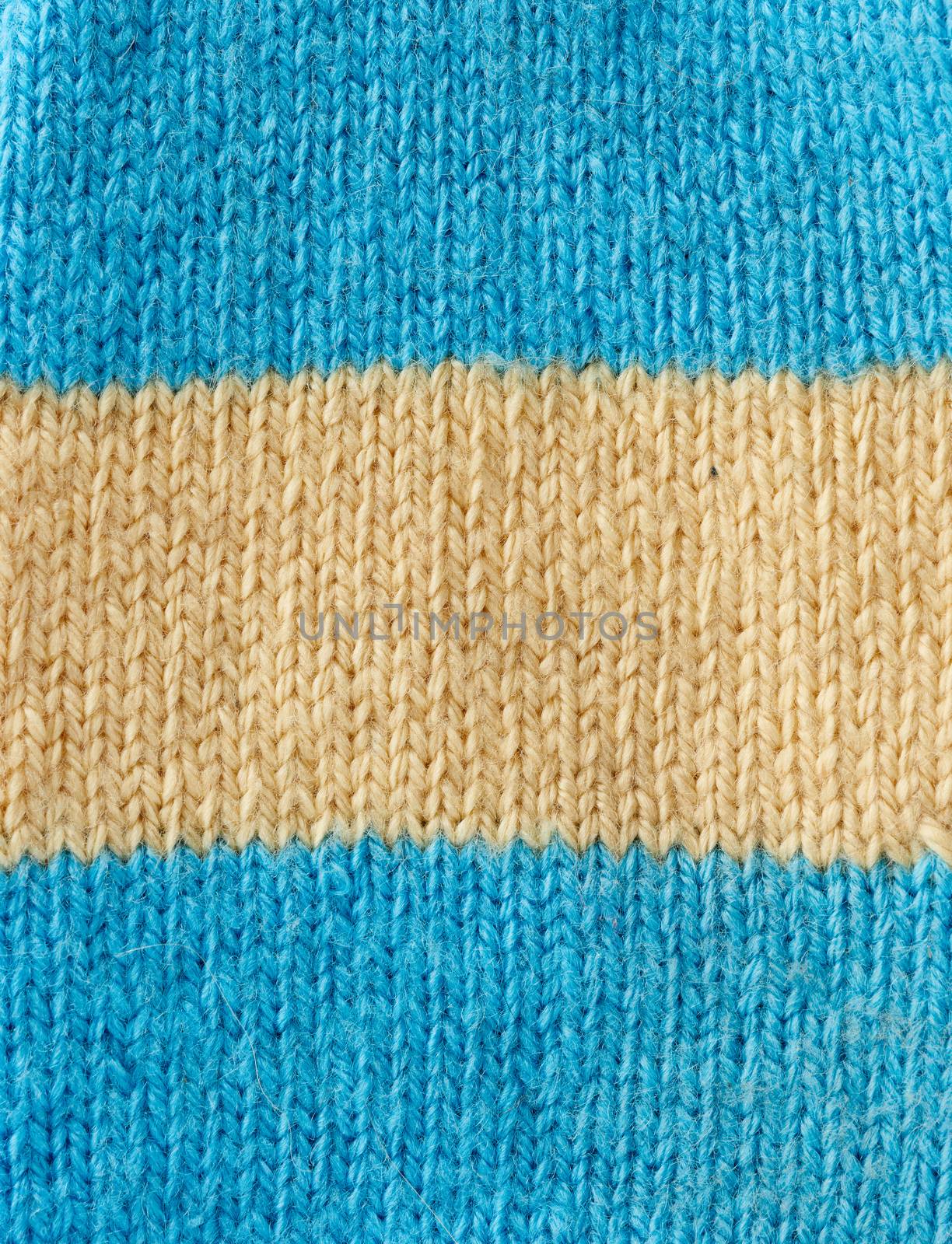 fragment of knitted fabric from blue and beige wool, pigtail pattern