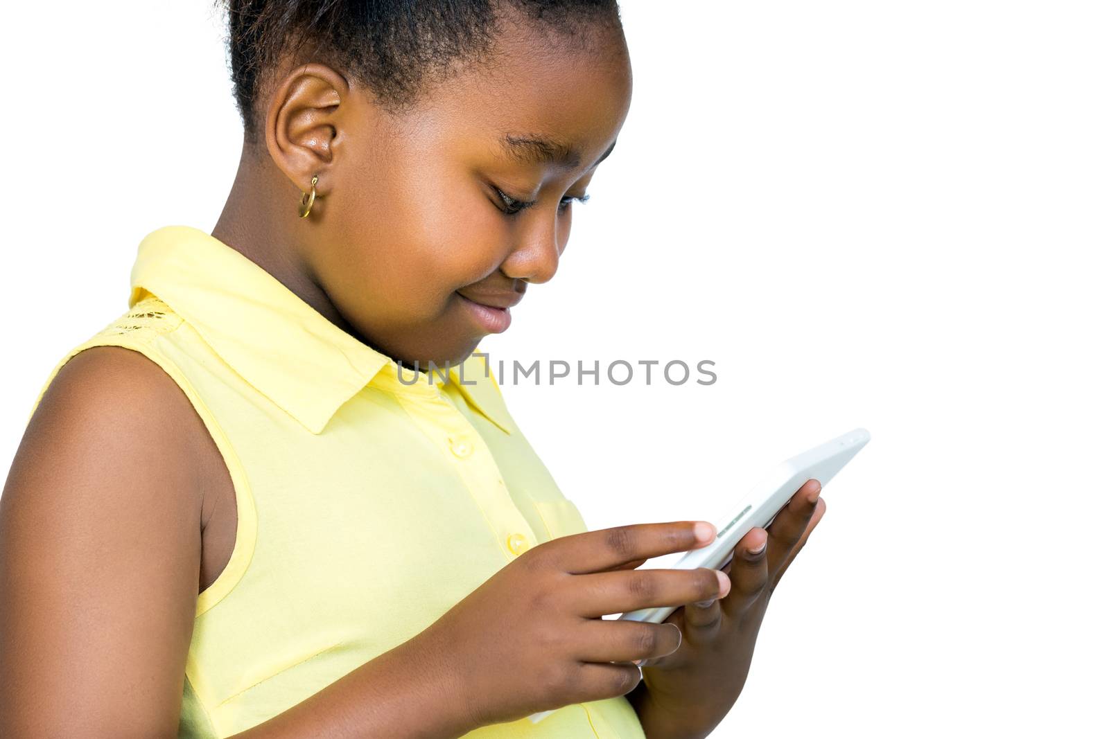 Close up portrait of cute little african girl with ponytail looking at digital tablet.Side view of kid Isolated on white background.