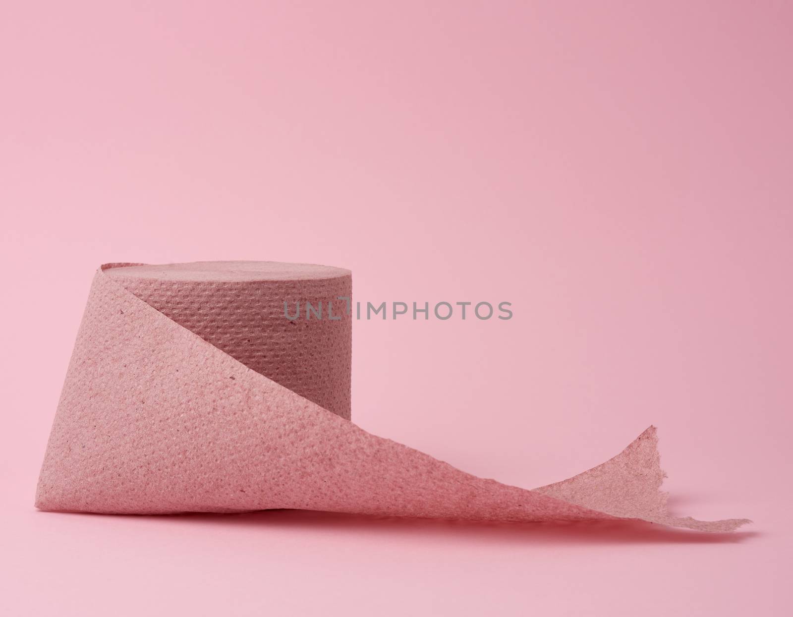 untwisted roll of pink toilet paper on a pink background, close up