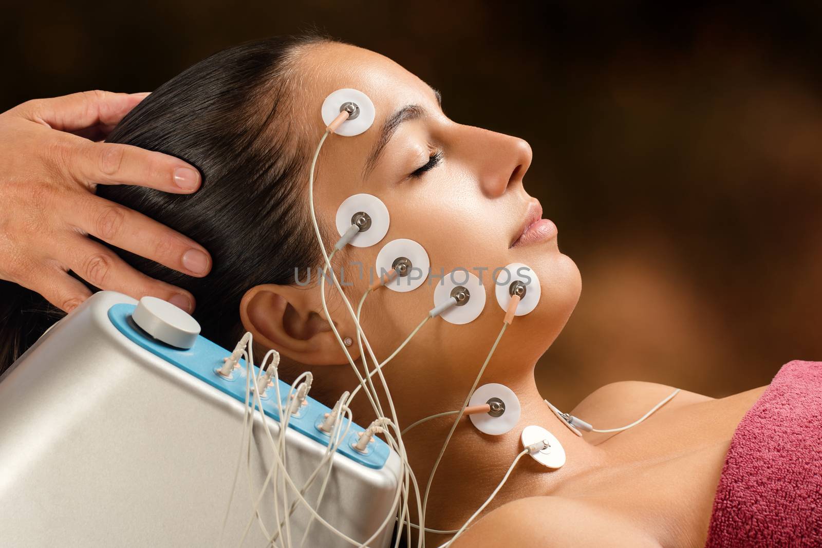 Close up portrait of woman having skin tightening treatment with low frequency electrodes. Hypo allergenic pads placed on woman’s face.