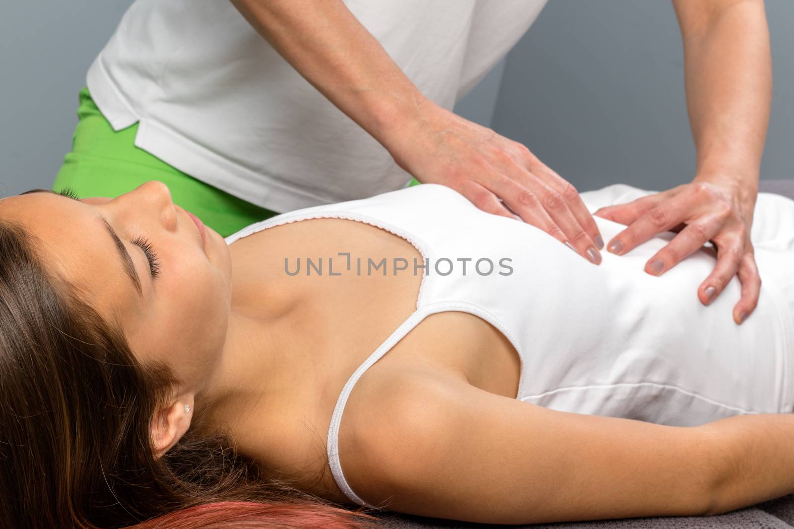 Close up of little girl at osteopathic treatment session. Therapist doing belly massage on child. 
