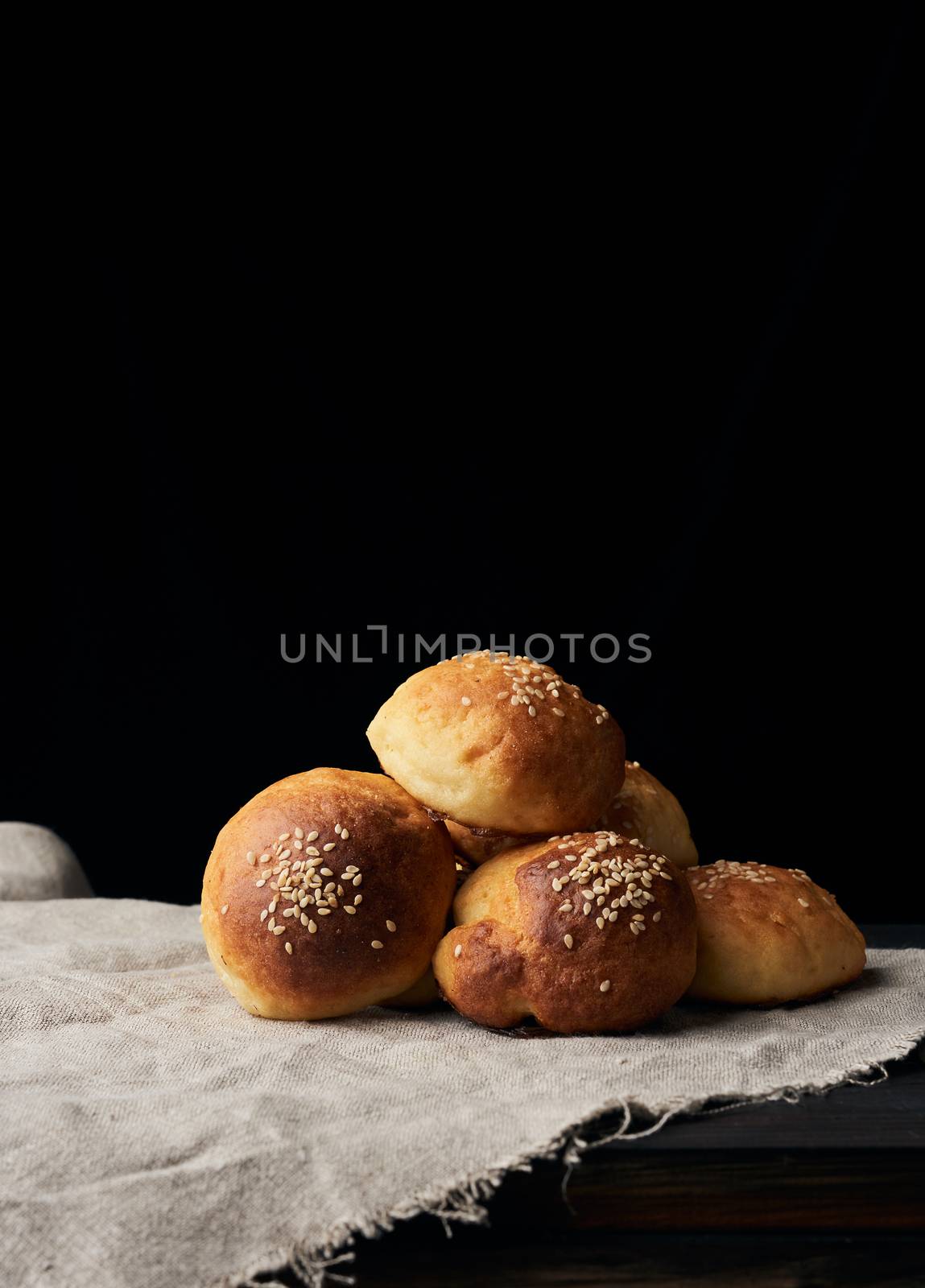 baked round bun with sesame seeds, black background, home baking by ndanko