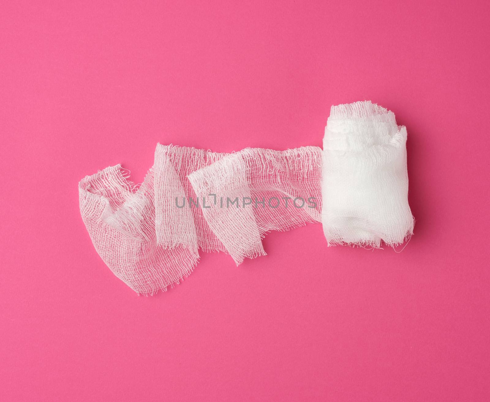 roll of white gauze bandage on a pink background, medical item for dressing human limbs