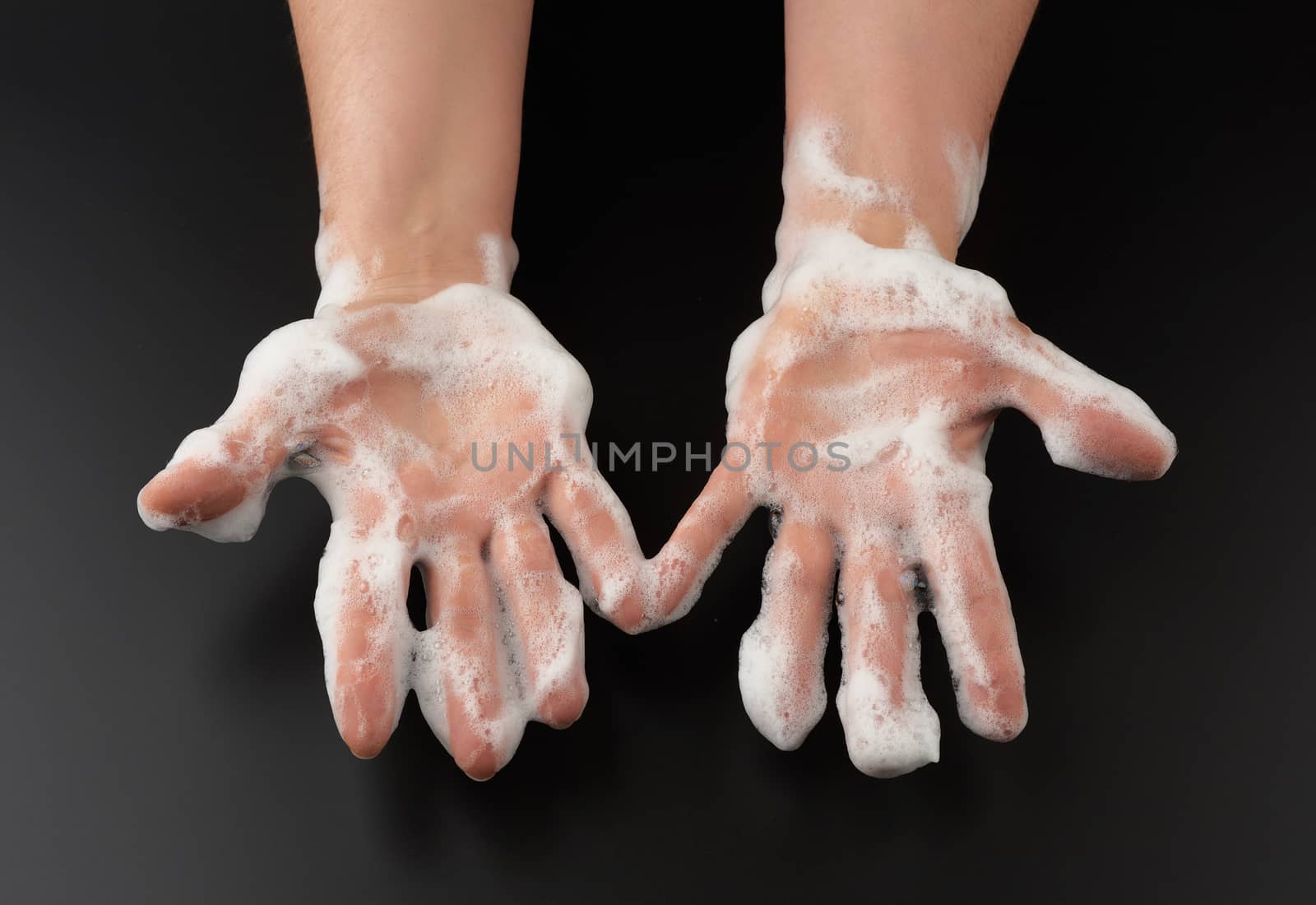 two female hands in white soap suds on a black background, concept of washing hands against bacteria, body care, top view