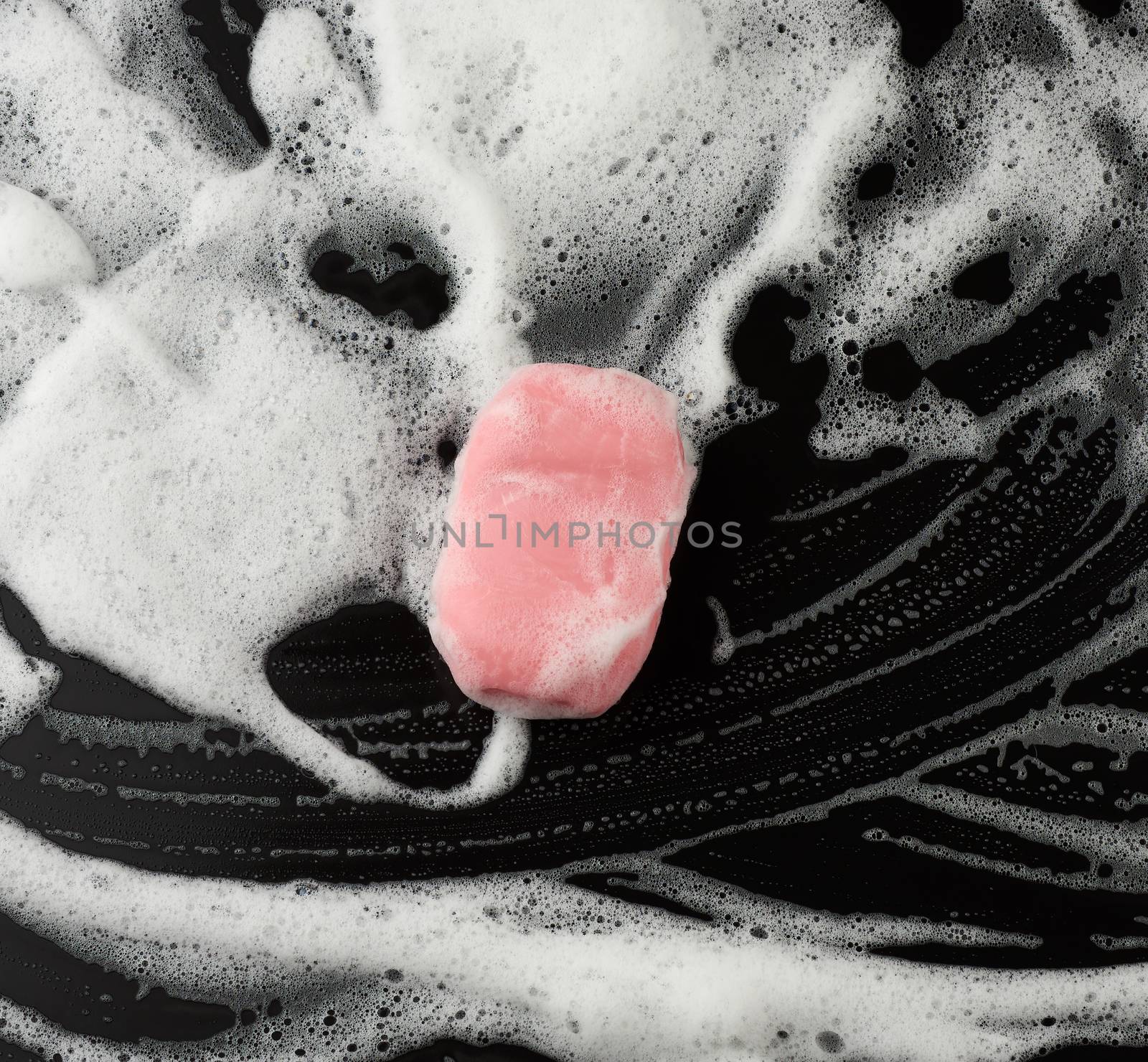 white soap foam and pink soap on a black background, top view, c by ndanko