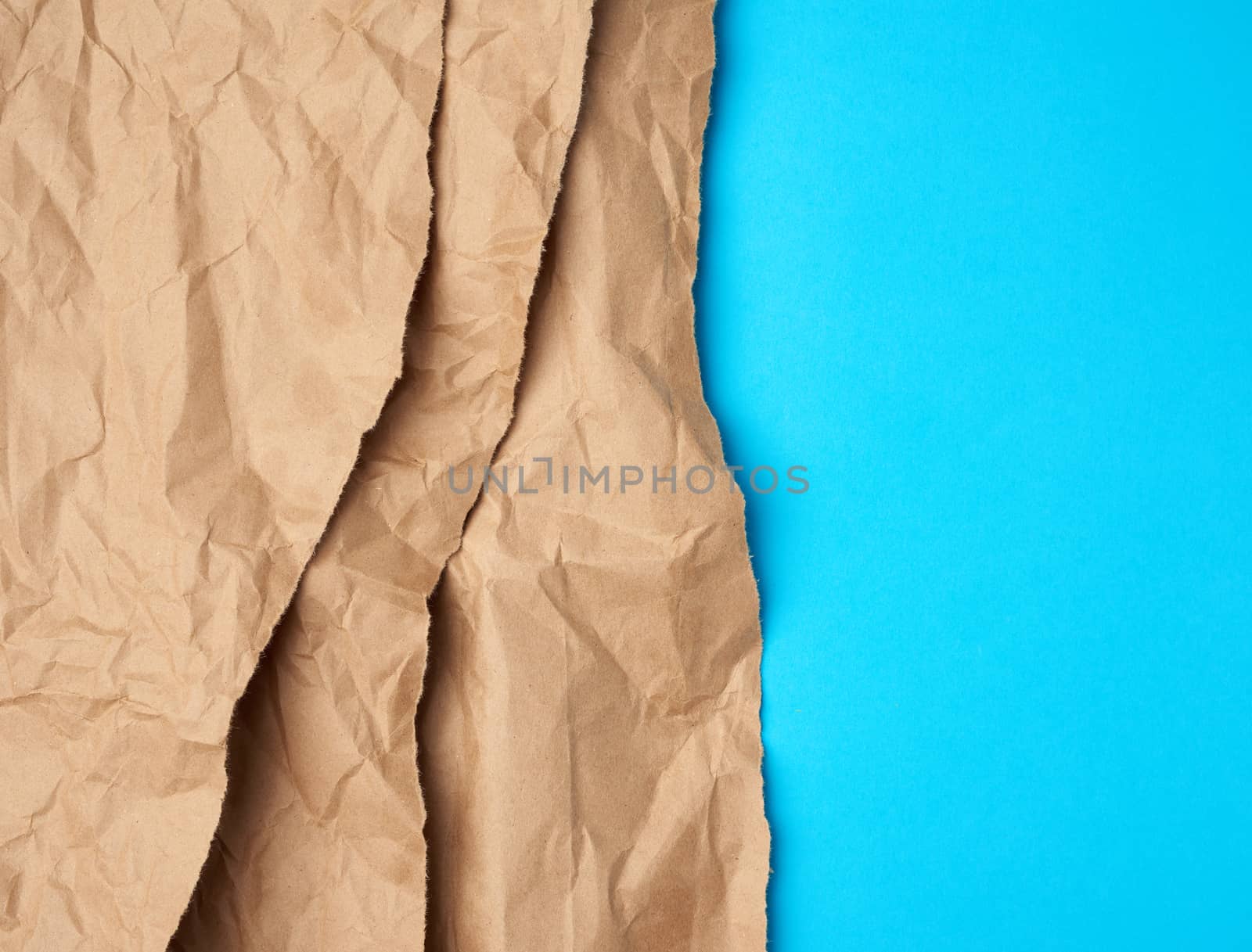 background of layered brown torn paper with a shadow on a blue background, backdrop and template for designer, copy space