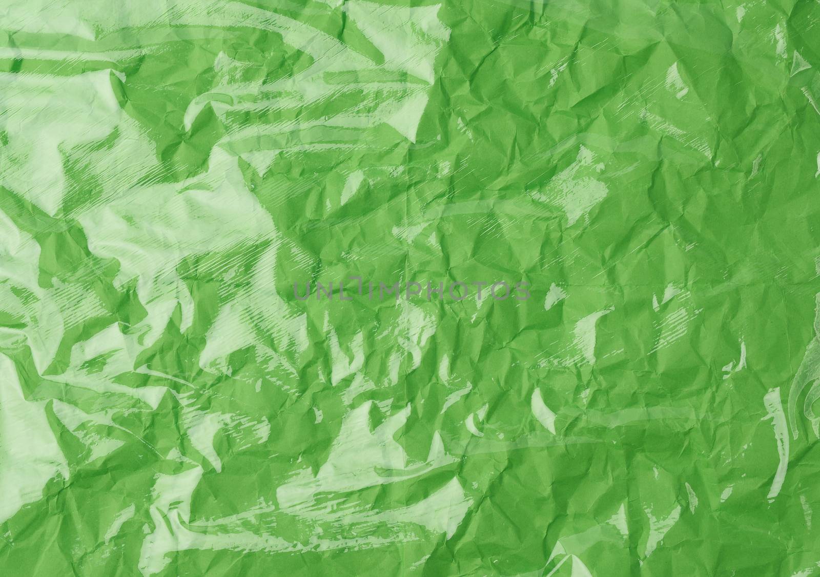 texture of a transparent stretching plastic film for packaging products on a green background, full frame, close up
