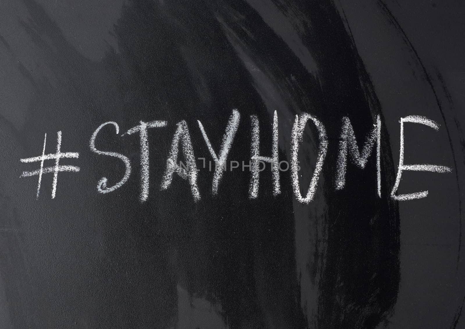 inscription stay home in chalk with a hashtag on a black chalk board, concept of self-isolation in an epidemic and pandemic