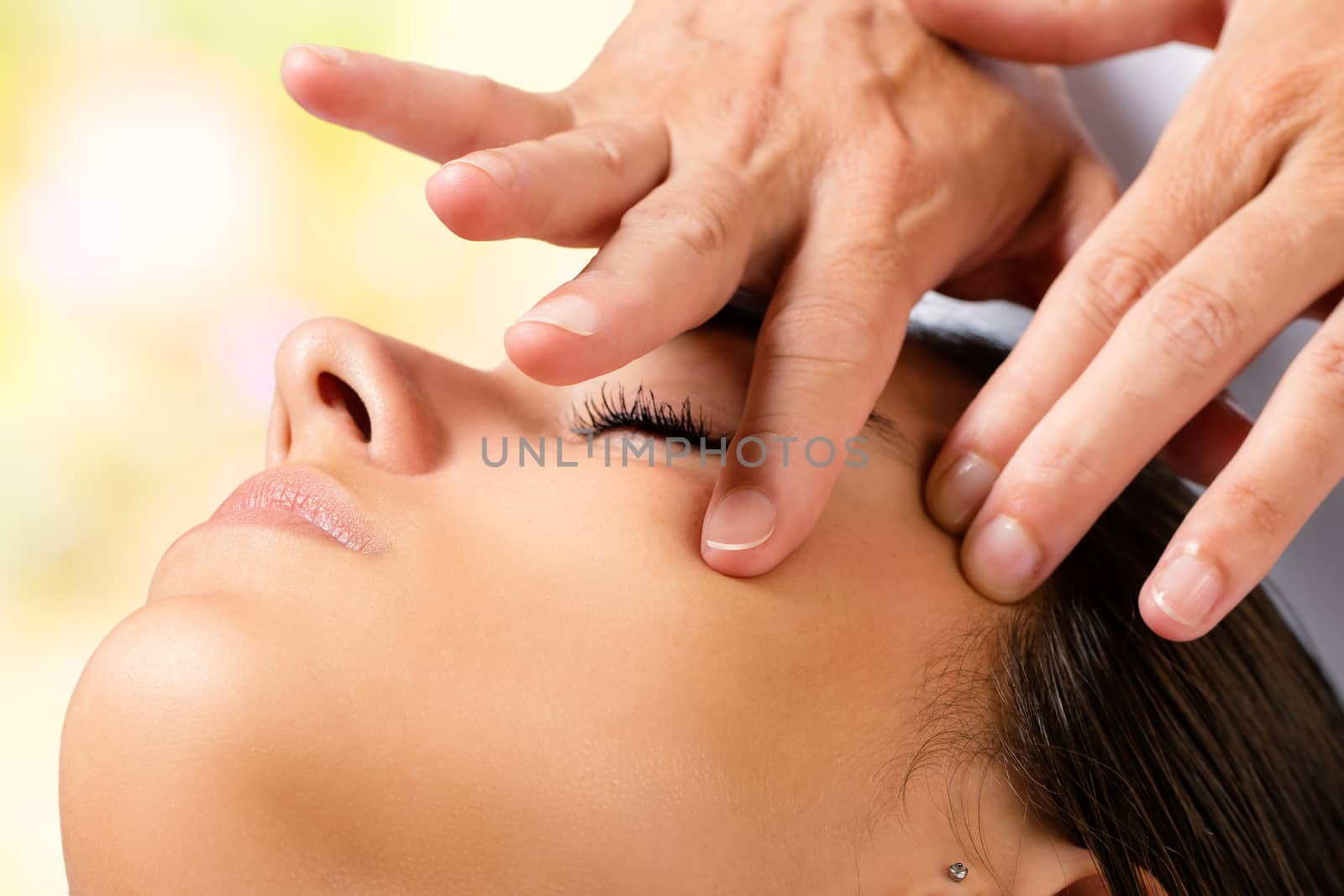 Extreme close up portrait of woman having beauty facial treatment. Therapist doing massage with product on cheek.