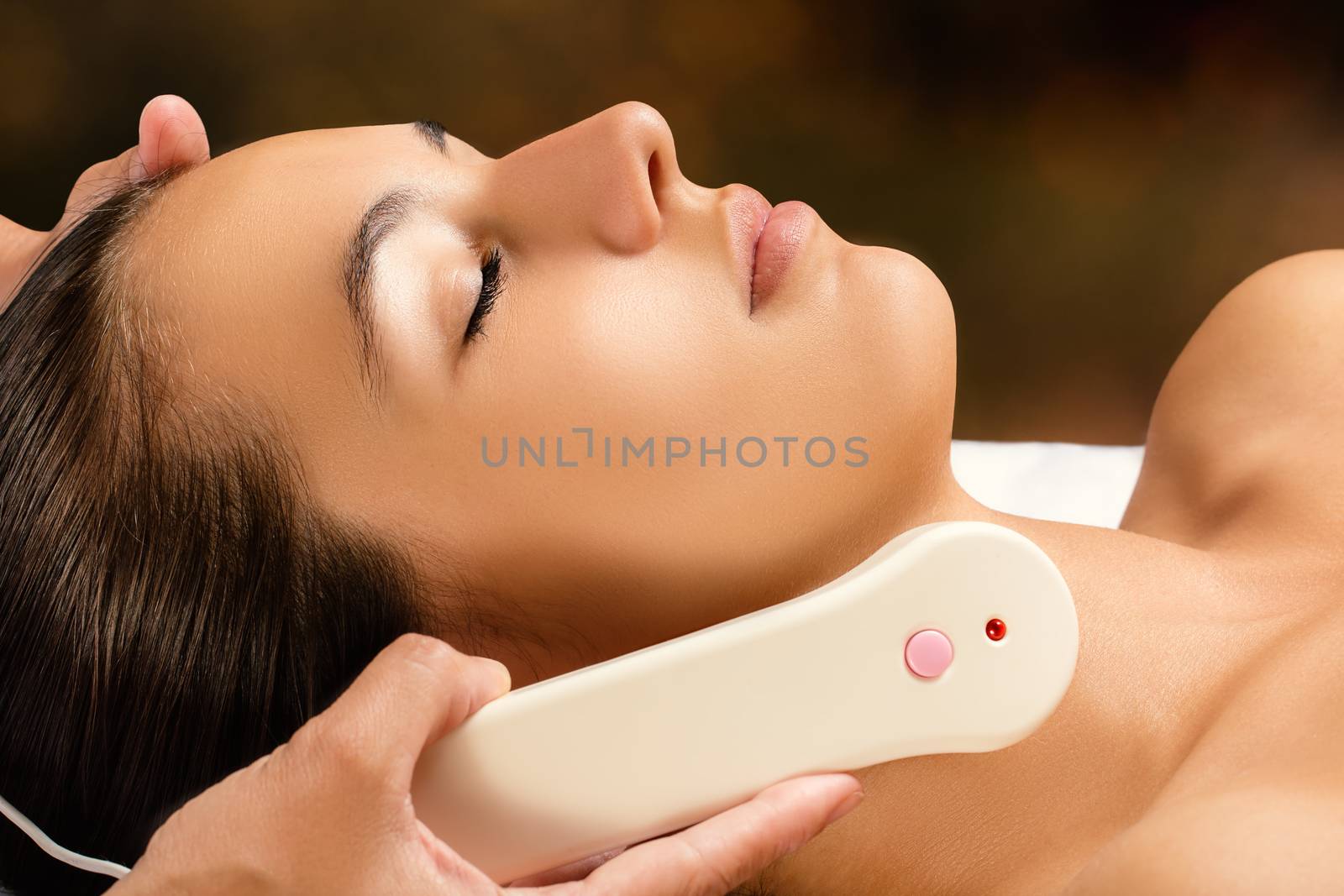 Woman receiving high frequency facial treatment. by karelnoppe