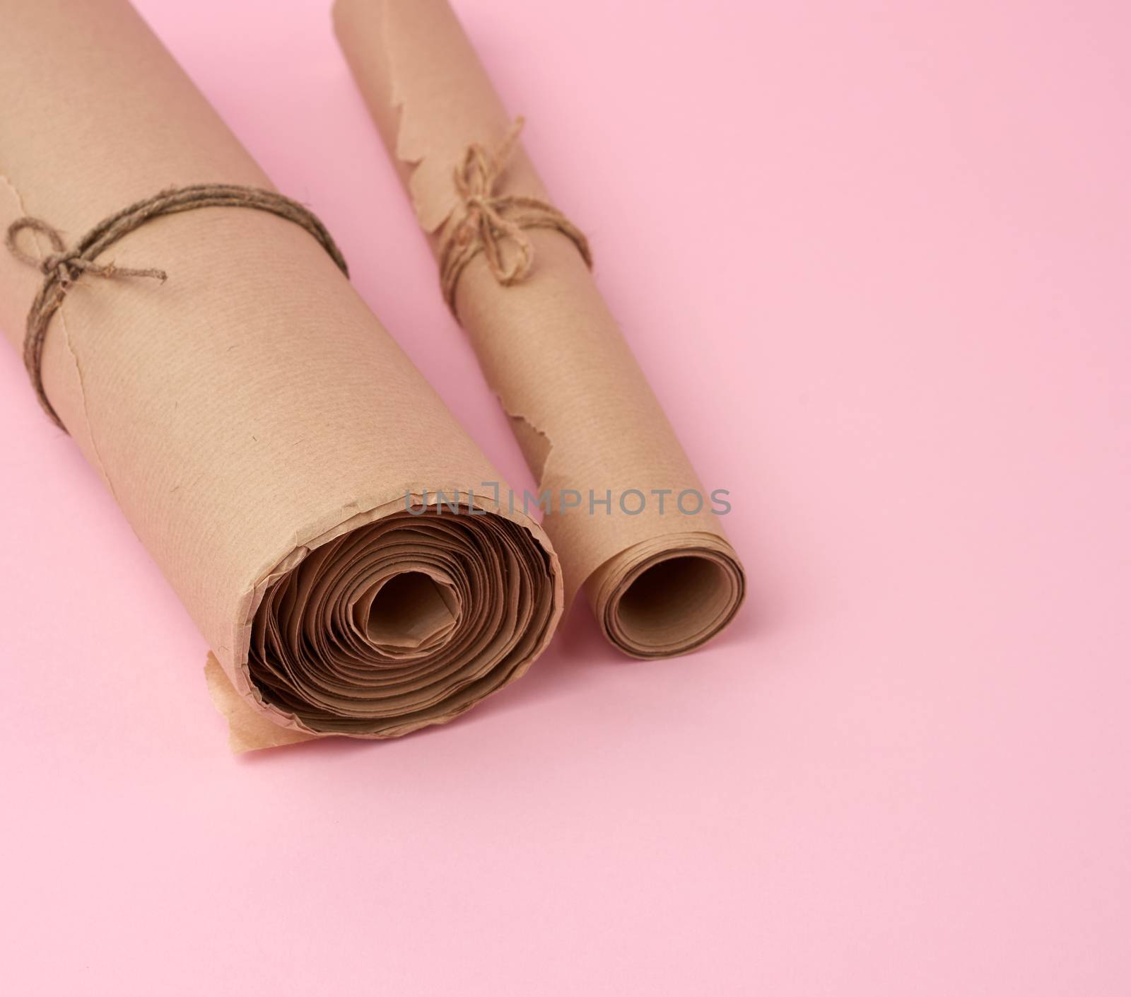 twisted rolls of brown paper on a pink background by ndanko