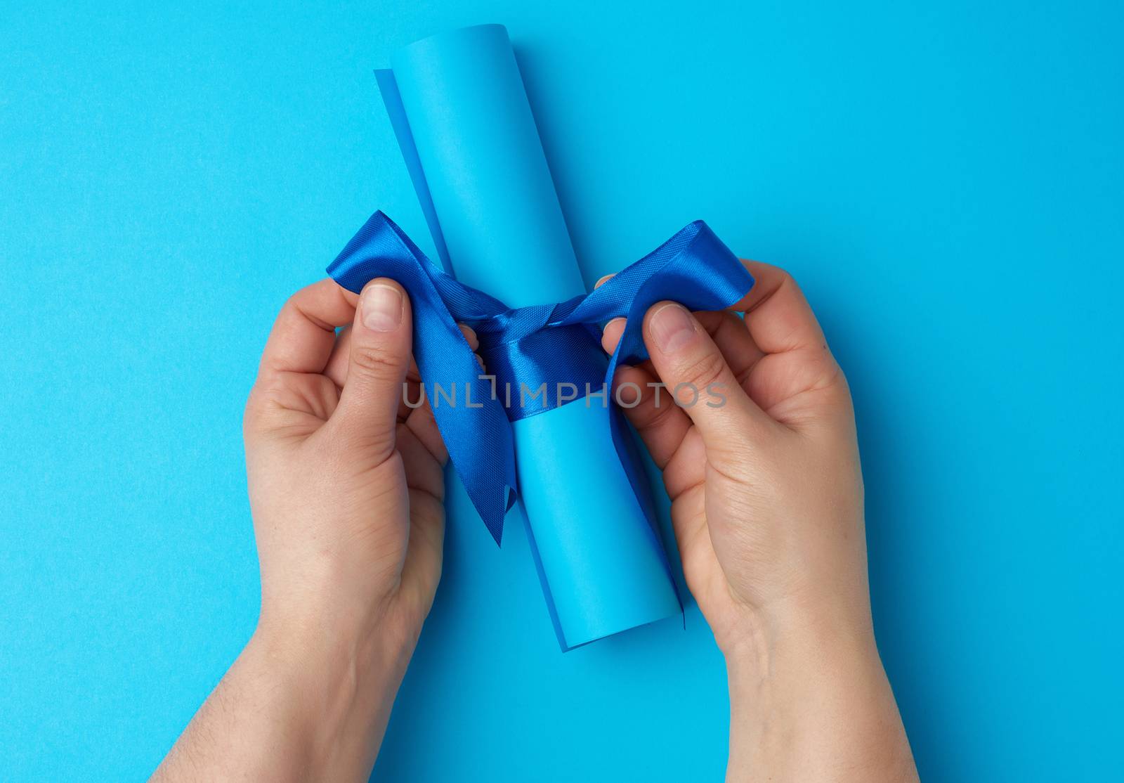 roll of blue paper tied with a silk blue ribbon, blue background, copy space