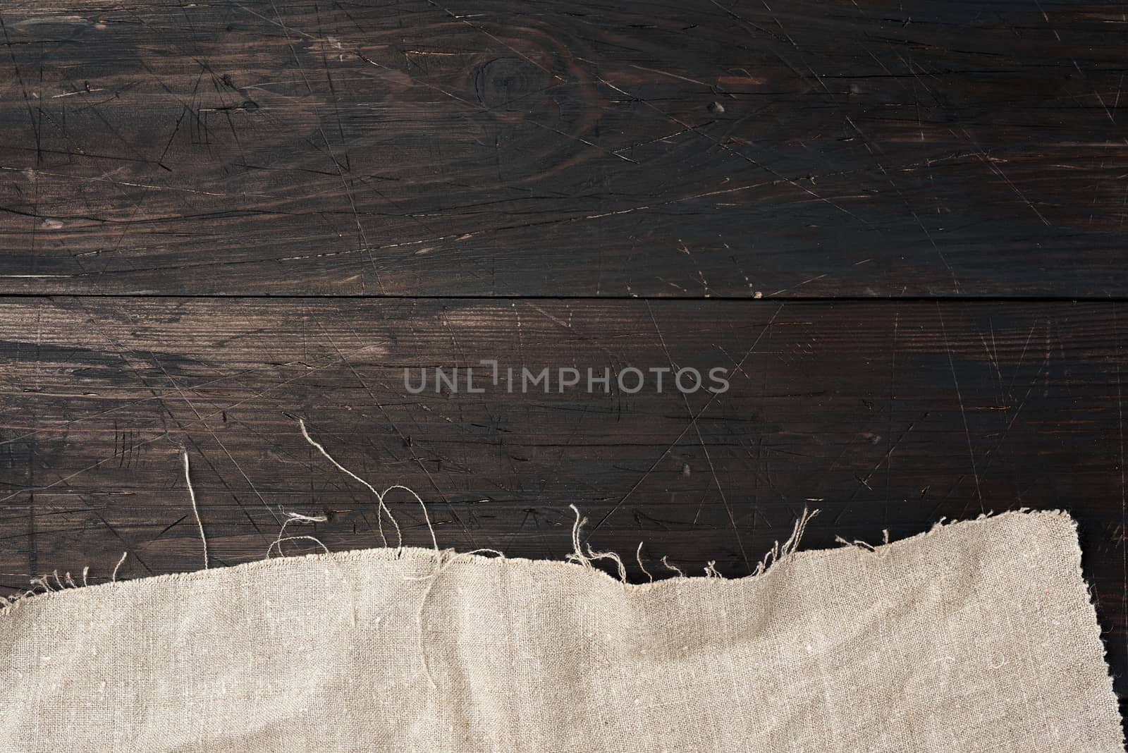 gray kitchen textile towel folded on a brown wooden table from old boards, top view, empty space. Rustic texture. Retro background
